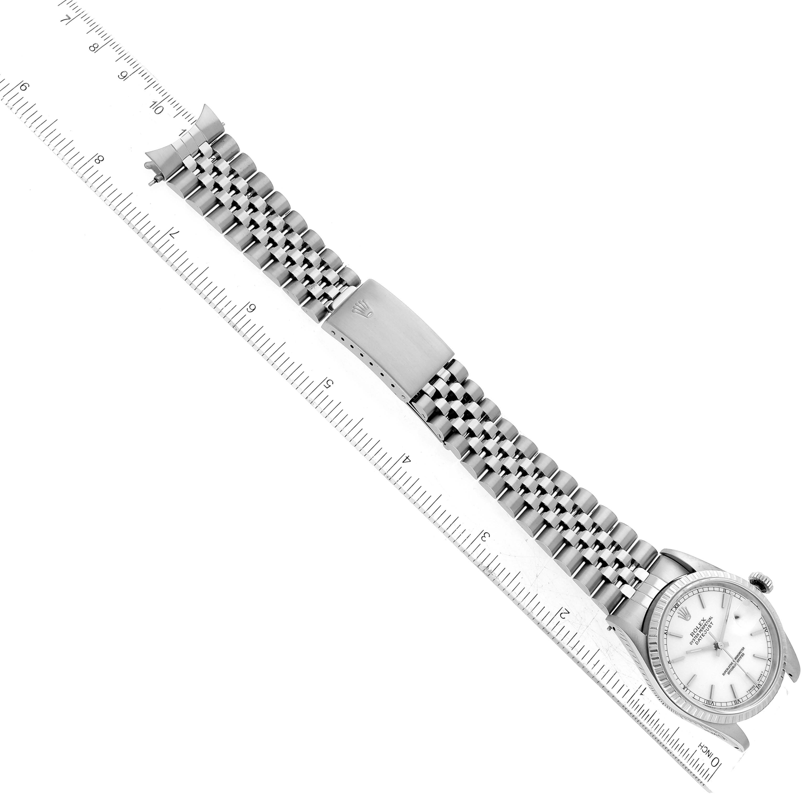The image shows a top view of a Rolex Datejust 16220 Men
s Stainless Steel White Dial 16220 Men
s Stainless Steel White Dial watch with its bracelet and clasp extended alongside a ruler for scale.