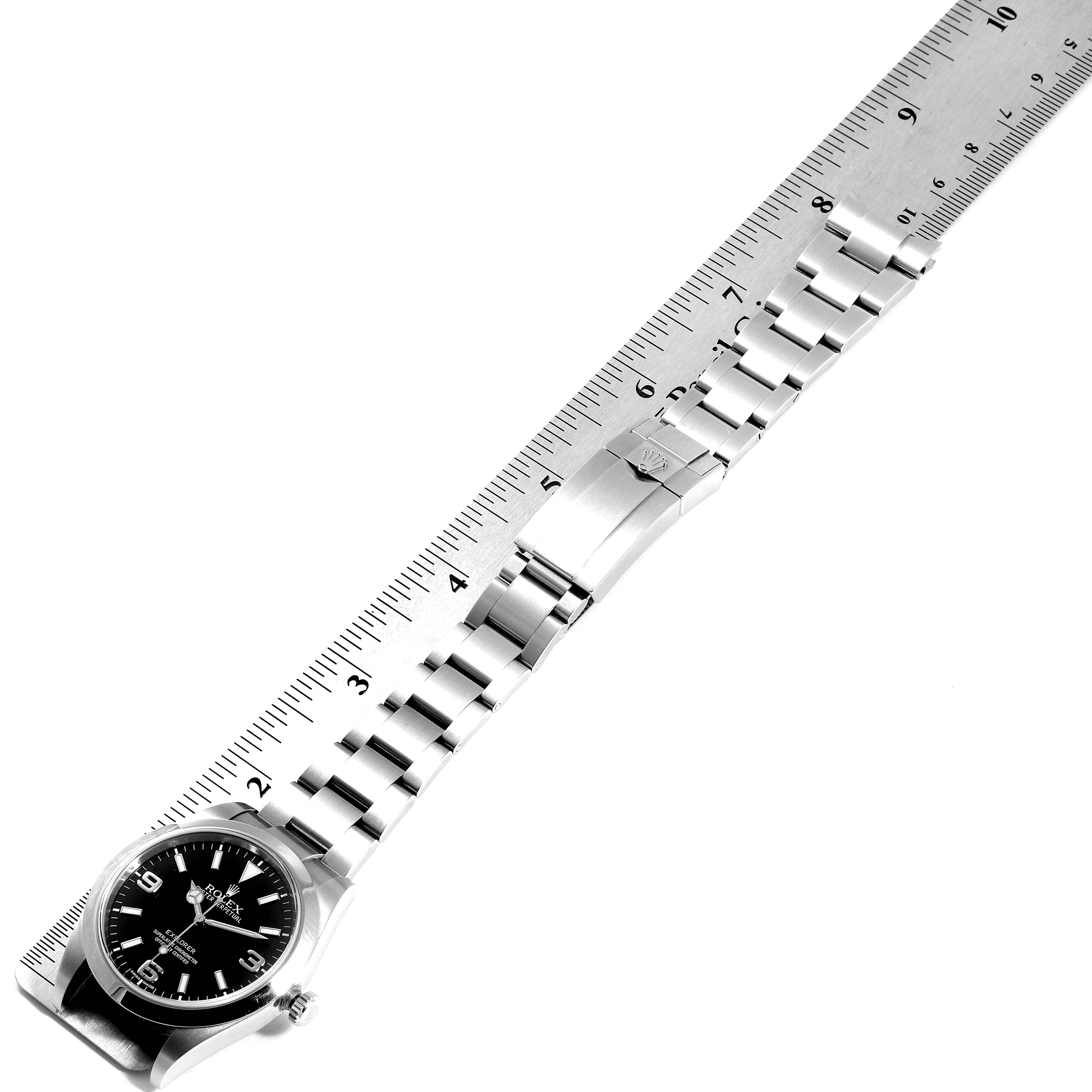 The image shows a top-down view of a Rolex Explorer 214270 Men
s Stainless Steel Black Dial 214270 Men
s Stainless Steel Black Dial watch with its bracelet extended along a ruler.