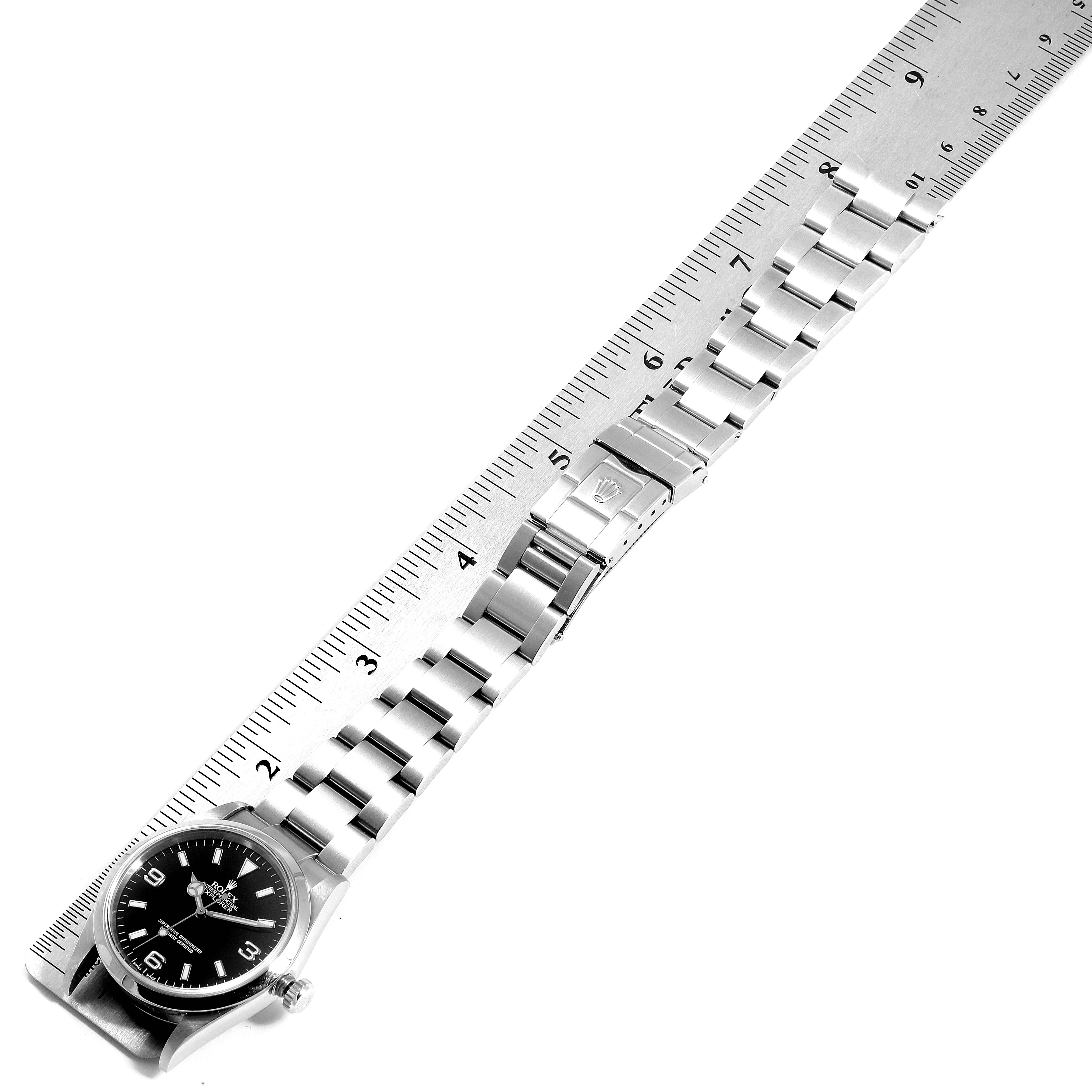 The Rolex Explorer 114270 Men
s Stainless Steel Black Dial 114270 Men
s Stainless Steel Black Dial watch is shown flat, with its bracelet aligned along a ruler for measurement.