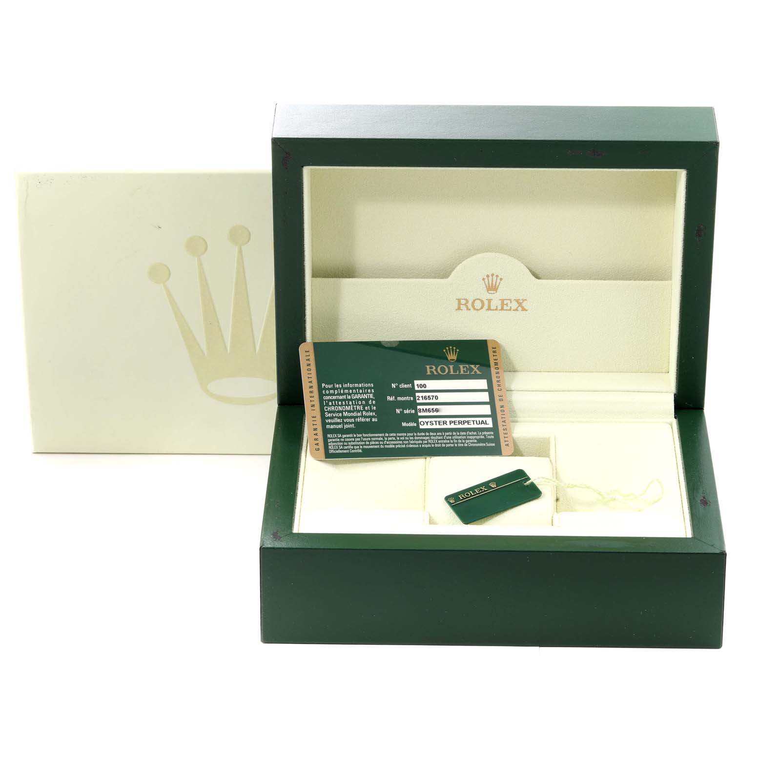 The image shows the interior of a Rolex Explorer 216570 Men
s Stainless Steel White Dial 216570 Men
s Stainless Steel White Dial model watch box with a warranty card and tag.
