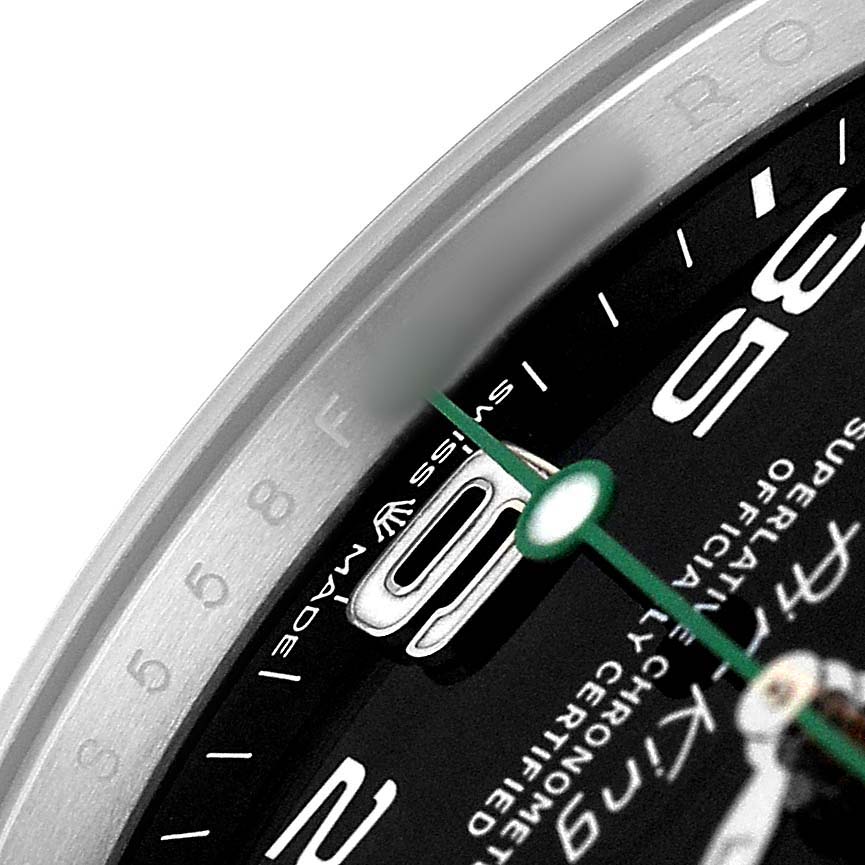 The image shows a close-up of the Rolex Air-King M126900-0001 Men's Stainless Steel Black Dial model's dial, focusing on the numerals, text, and the minute hand.