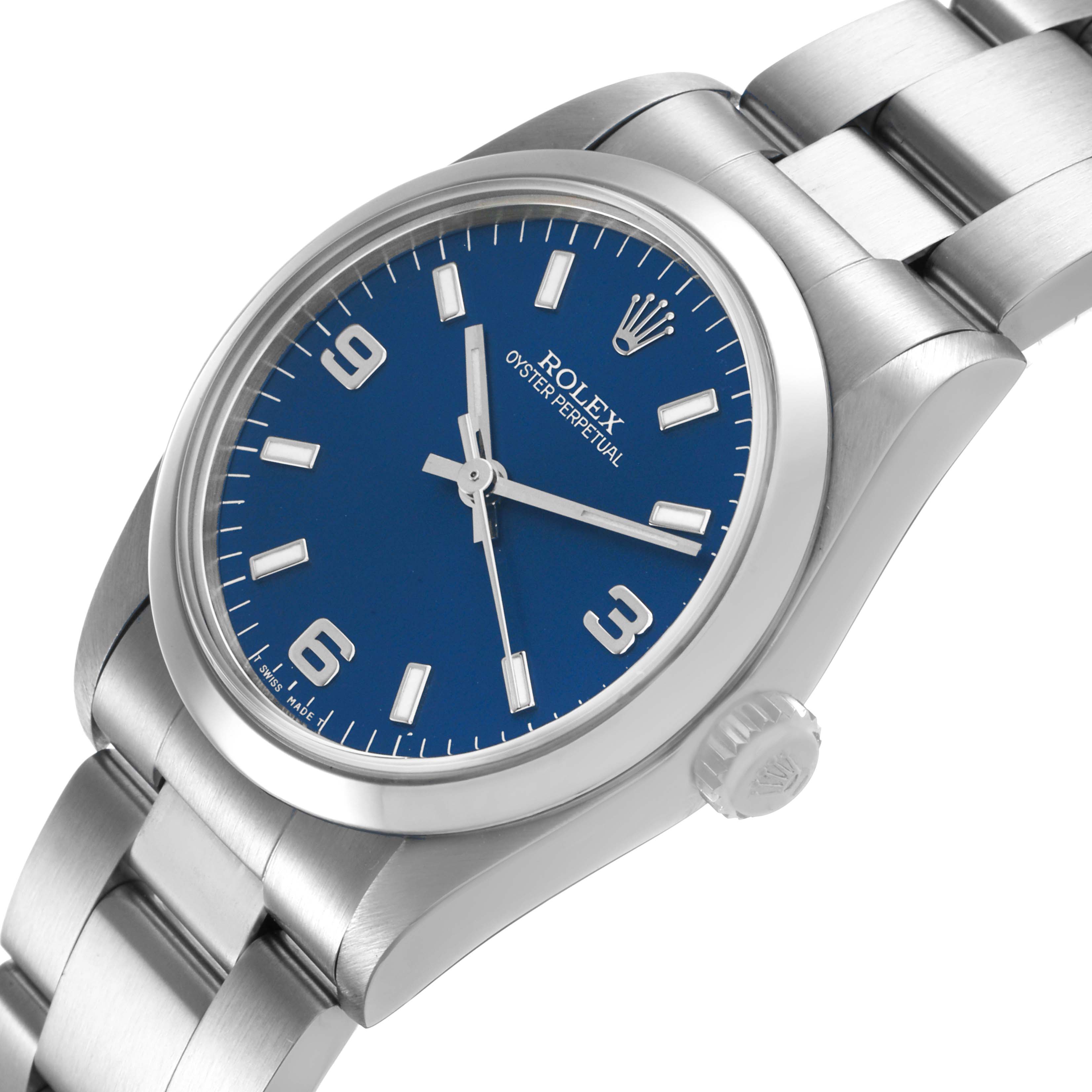 The image shows a Rolex Mid-Size 67480 Women's Stainless Steel Blue Dial watch at a three-quarter angle, highlighting the blue dial, hour markers, bracelet, and crown.