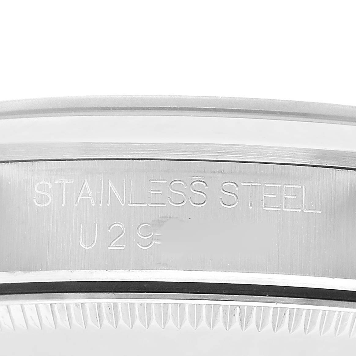 The image shows a close-up of the side of a Rolex Mid-Size 67480 Women's Stainless Steel Blue Dial watch case engraved with "STAINLESS STEEL" and a serial number.