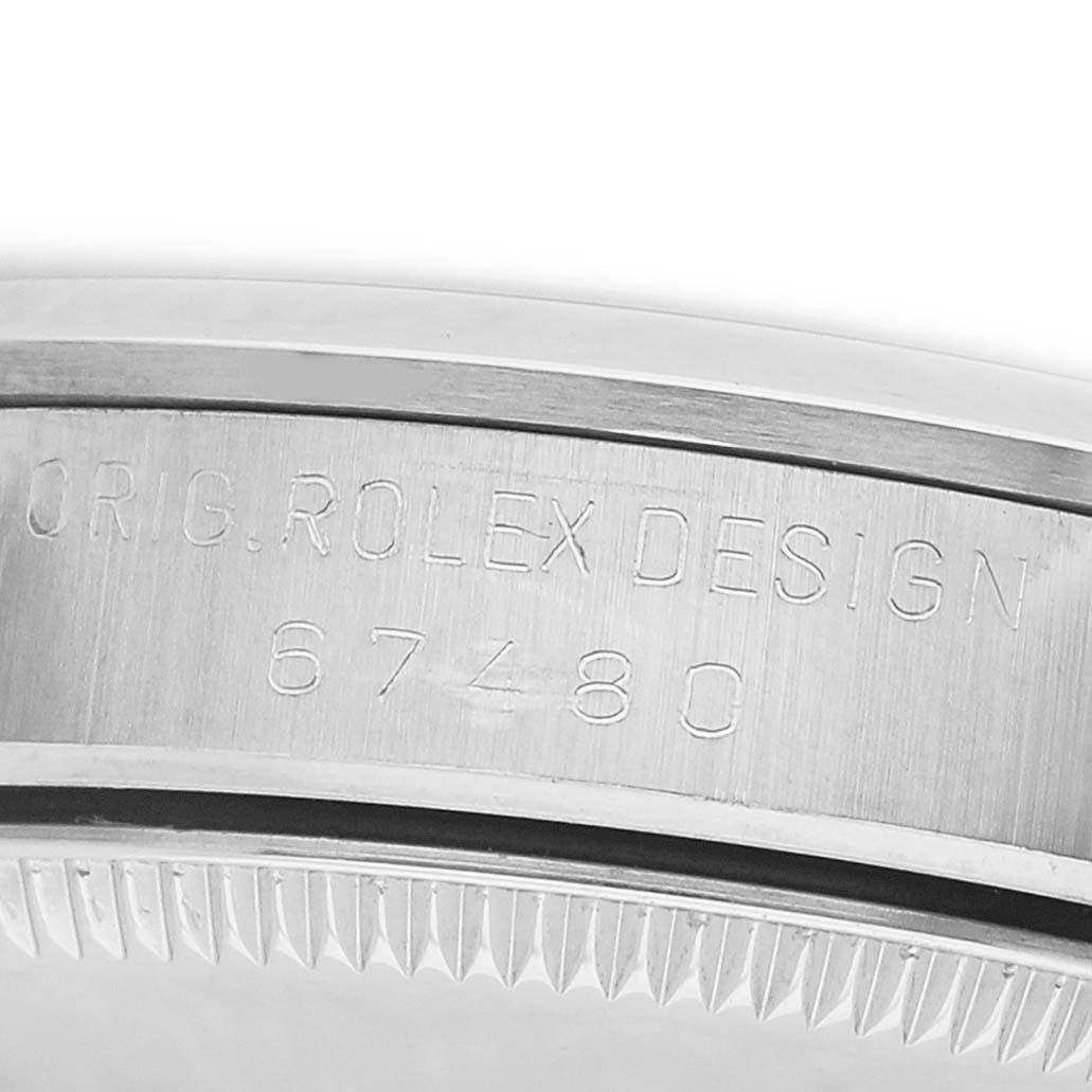 The image shows a close-up of the side of a Rolex Mid-Size 67480 Women's Stainless Steel Pink Dial model, focusing on the engraved bezel area.