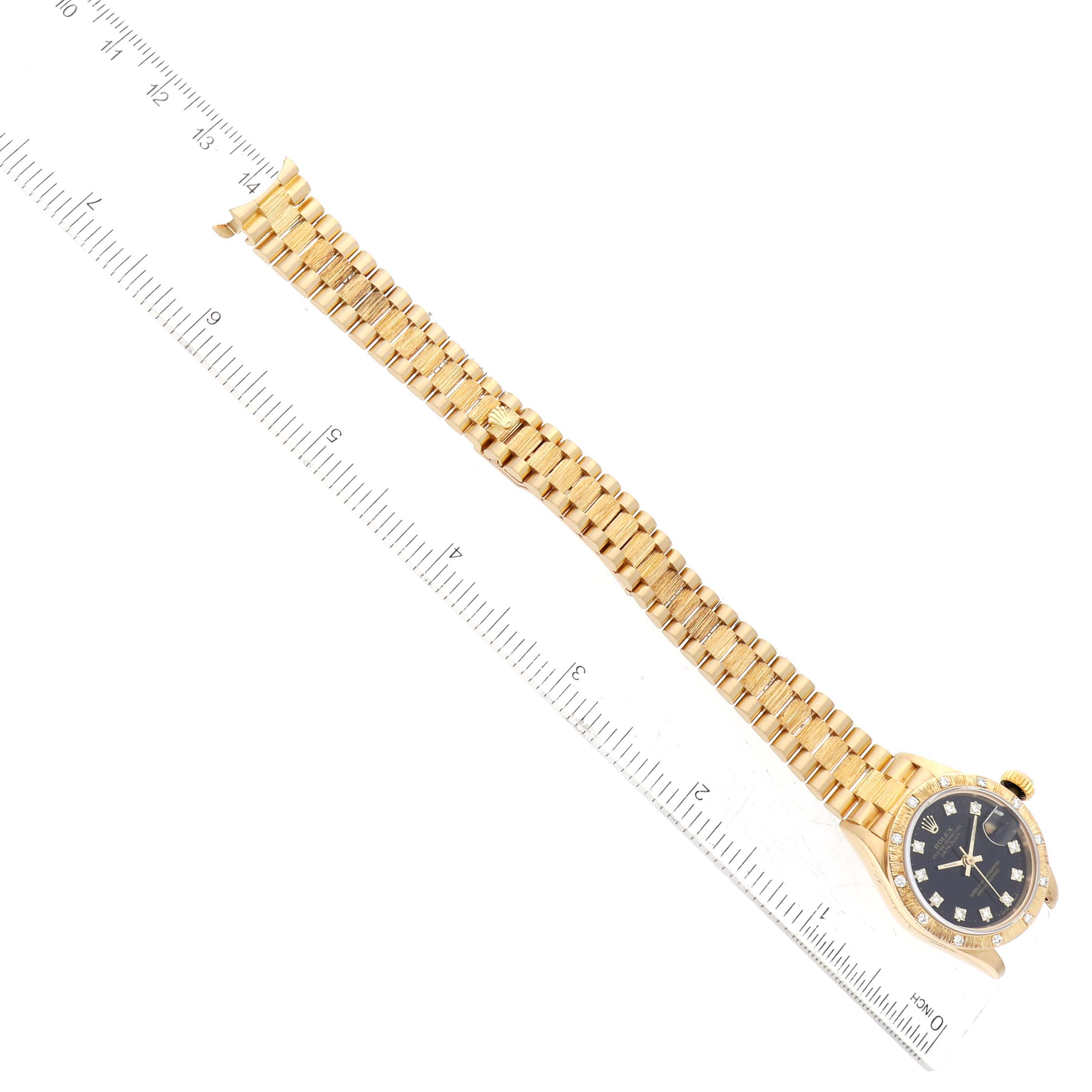 The image shows a Rolex President 69288G Women's Yellow Gold Black Dial 69288G Women's Yellow Gold Black Dial model watch lying flat next to a ruler, displaying its full length and gold bracelet.
