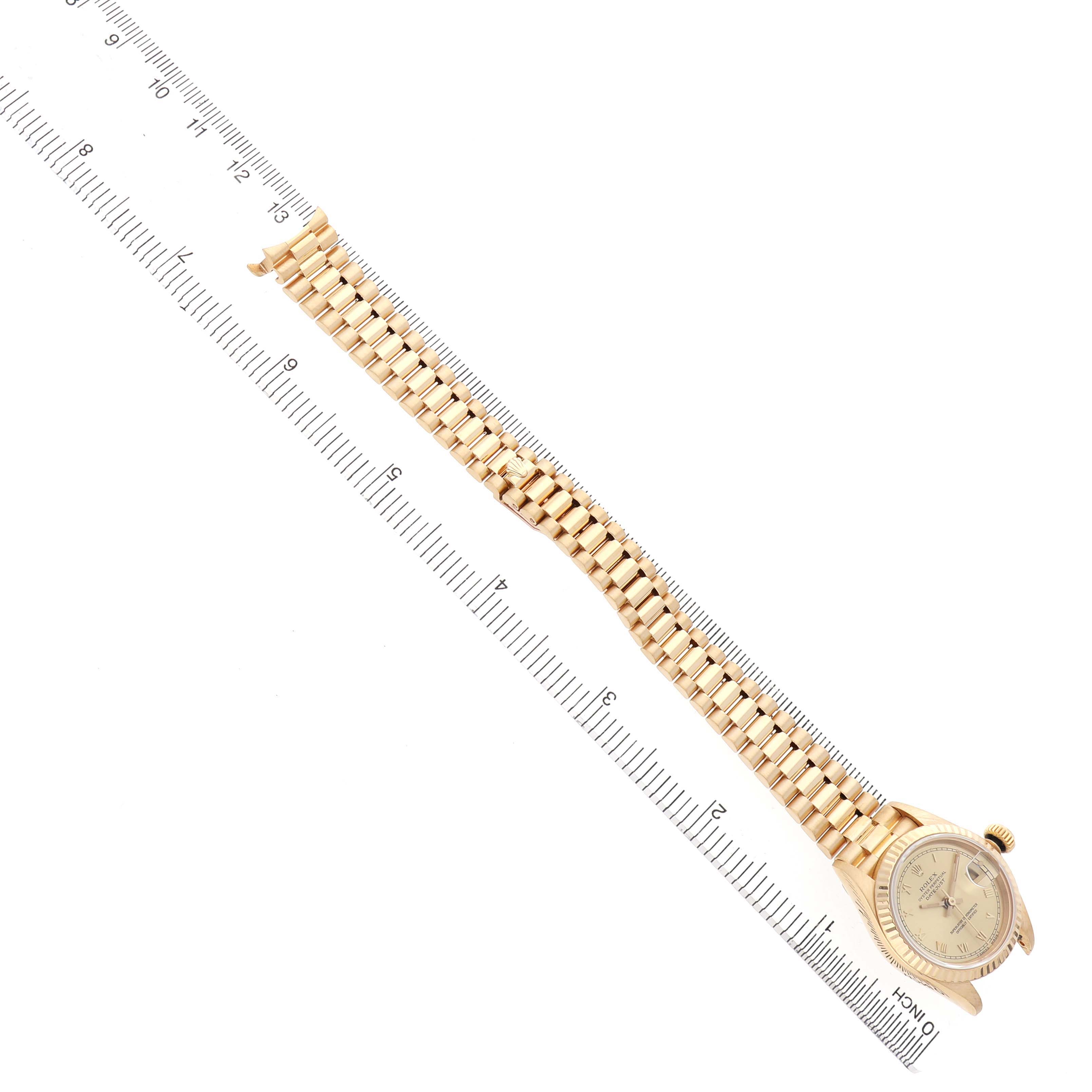 The image shows a Rolex President 69178 Women's Yellow Gold Champagne Dial watch laid flat at an angle, displaying its face, case, and full bracelet alongside a ruler for scale.