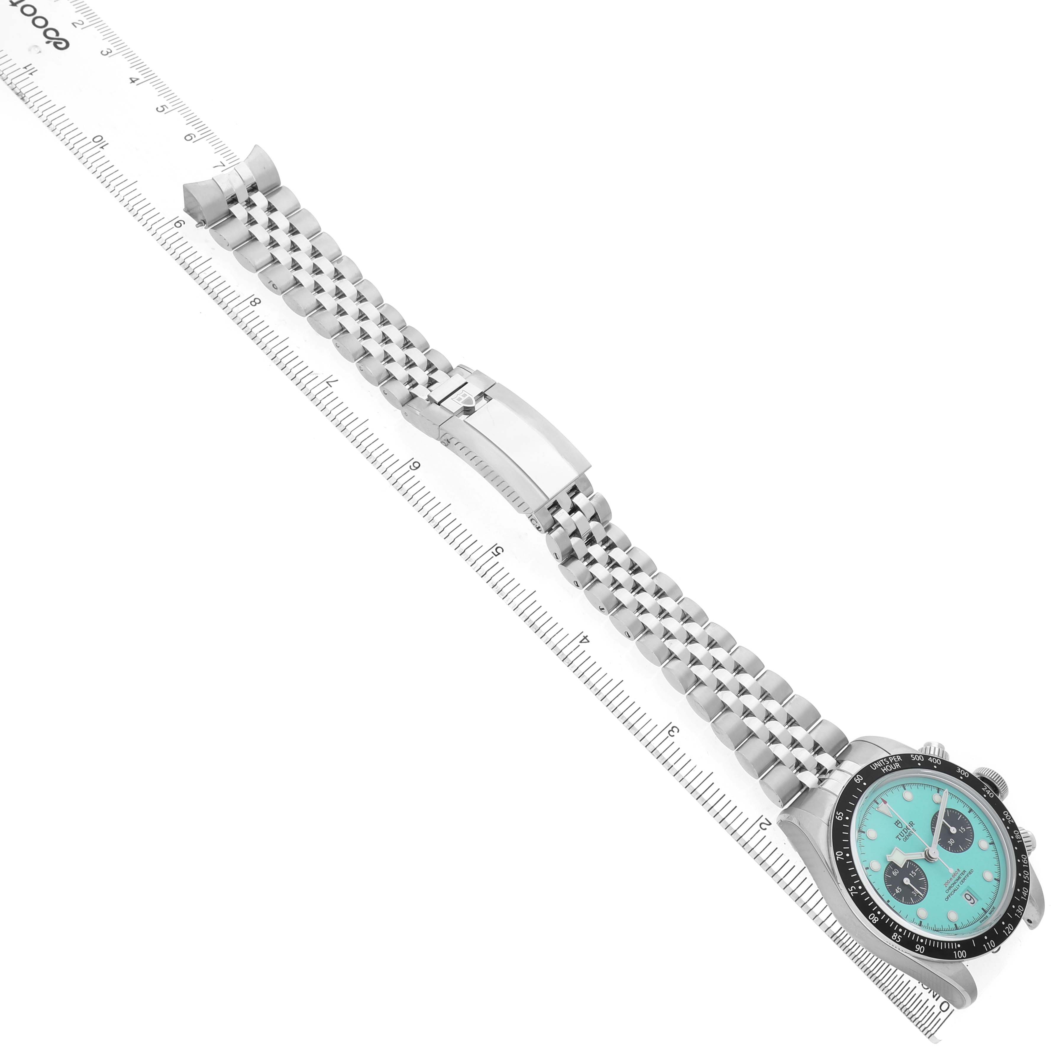The Tudor Heritage Chrono 79360N Men's Stainless Steel Blue Dial watch is shown from a top angle, highlighting the face, bezel, and stainless steel bracelet alongside a ruler.