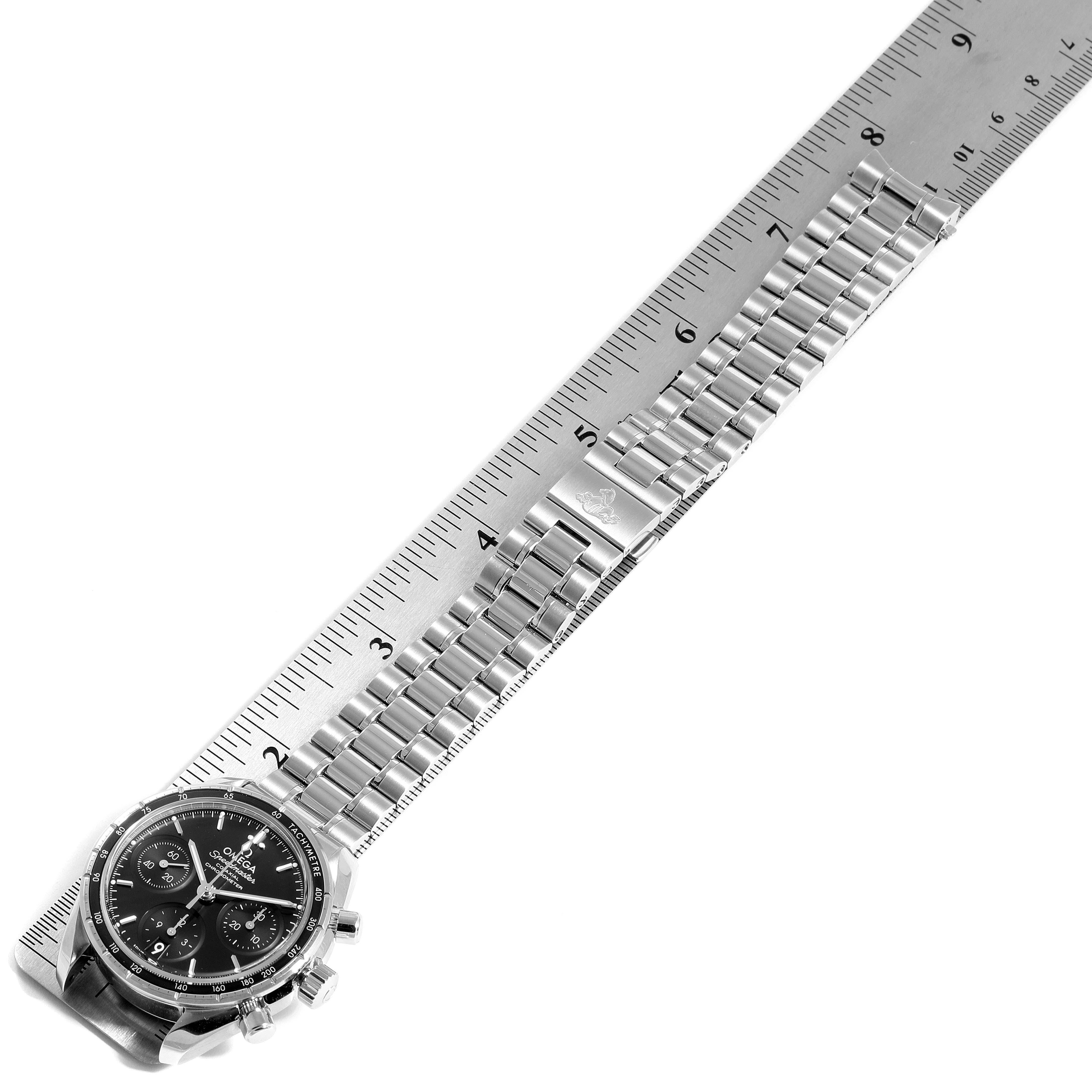 The image shows the Omega Speedmaster 324.30.38.50.01.001 Men
s Stainless Steel Black Dial 324.30.38.50.01.001 Men
s Stainless Steel Black Dial watch from an above angle, displaying the entire band and face next to a ruler.