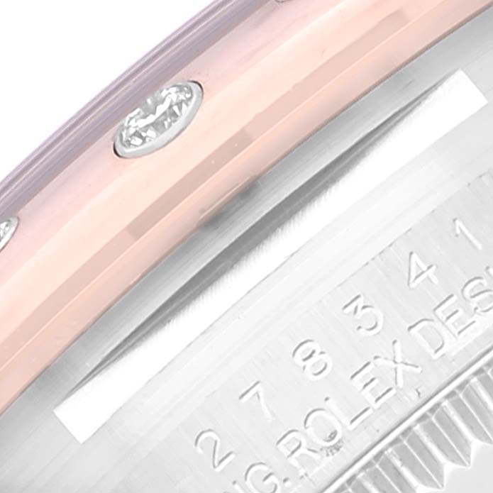 The image shows a close-up of the bezel and part of the case back of the mid-size Rolex watch, highlighting some diamond markers and engravings.