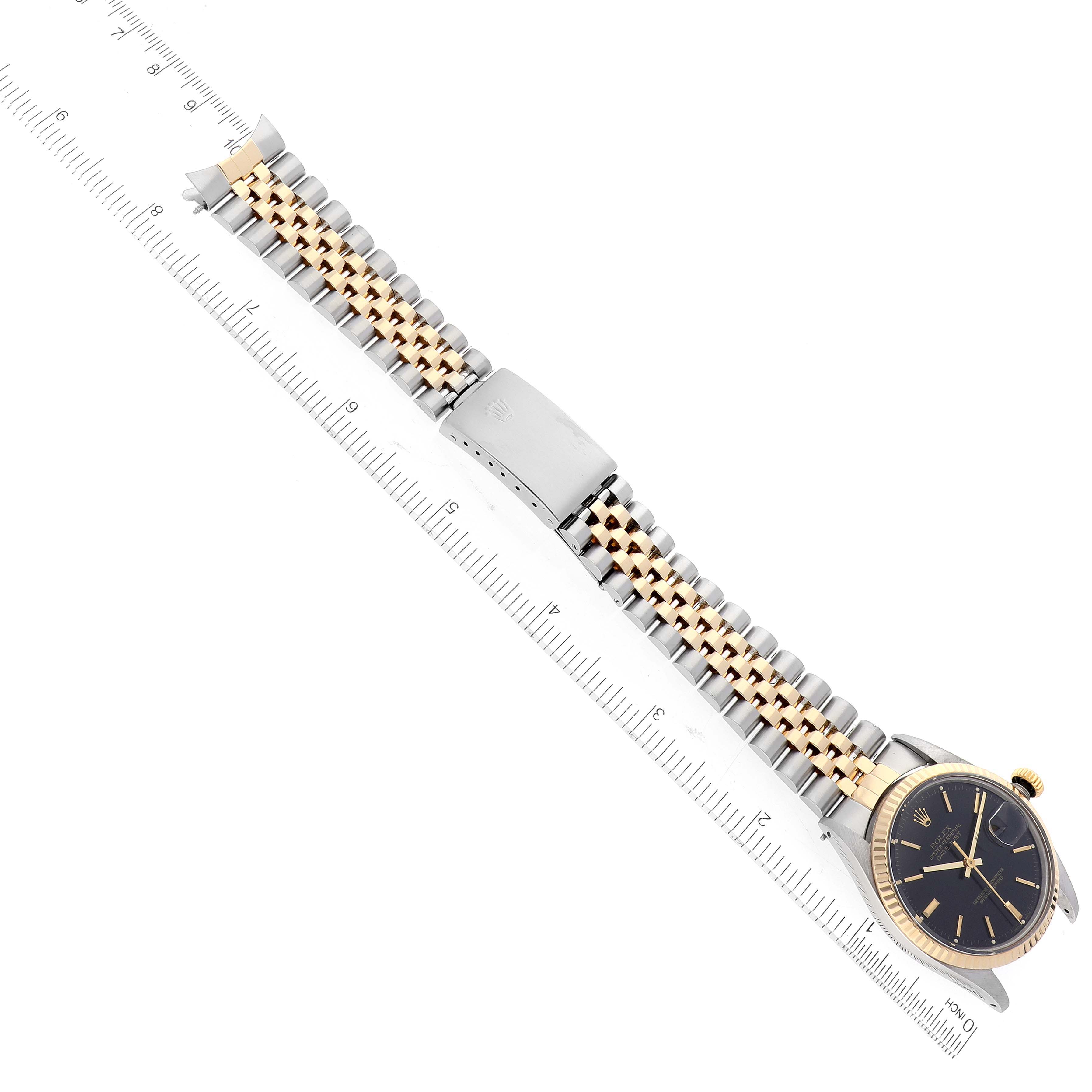 The image shows a vertical view of the Rolex Vintage Collection 16013 Men's Steel and Gold (two tone) Black Dial 16013 Men's Steel and Gold (two tone) Black Dial watch displaying its dial, bezel, and band laid flat against a ruler.
