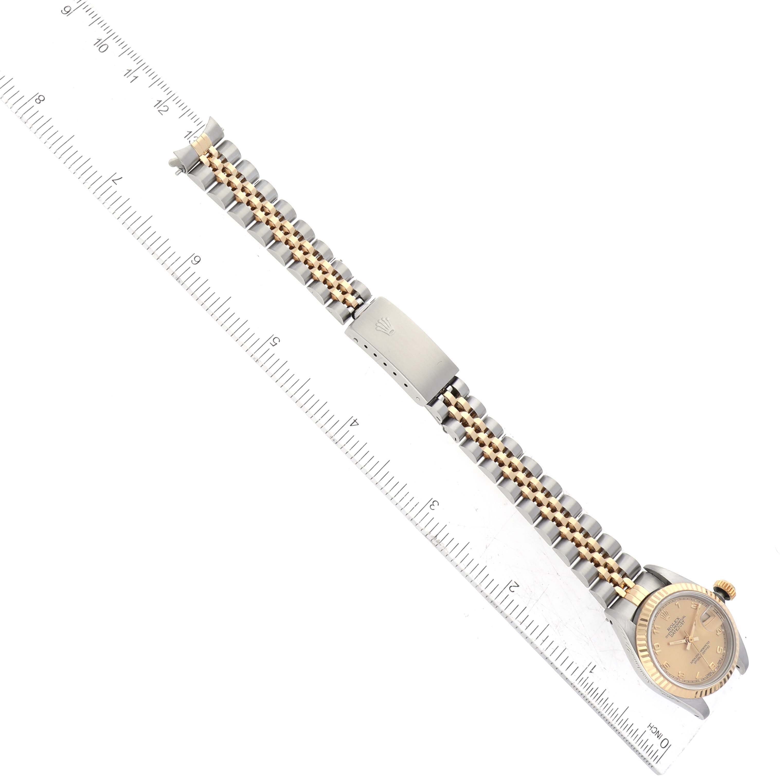 The Rolex Datejust 69173G Women's Steel and Gold (two tone) Champagne Dial 69173G Women's Steel and Gold (two tone) Champagne Dial watch is shown from a top-down angle, displaying the face, bracelet, and clasp, with a ruler for scale.