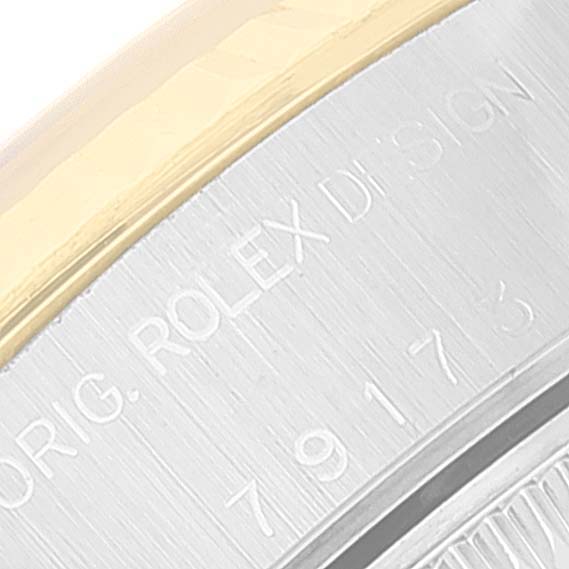 The image displays a close-up angle of a Rolex Datejust 79173 Women
s Steel and Gold (two tone) Champagne Dial 79173 Women
s Steel and Gold (two tone) Champagne Dial watch case, highlighting the engraved text and part of the bezel.
