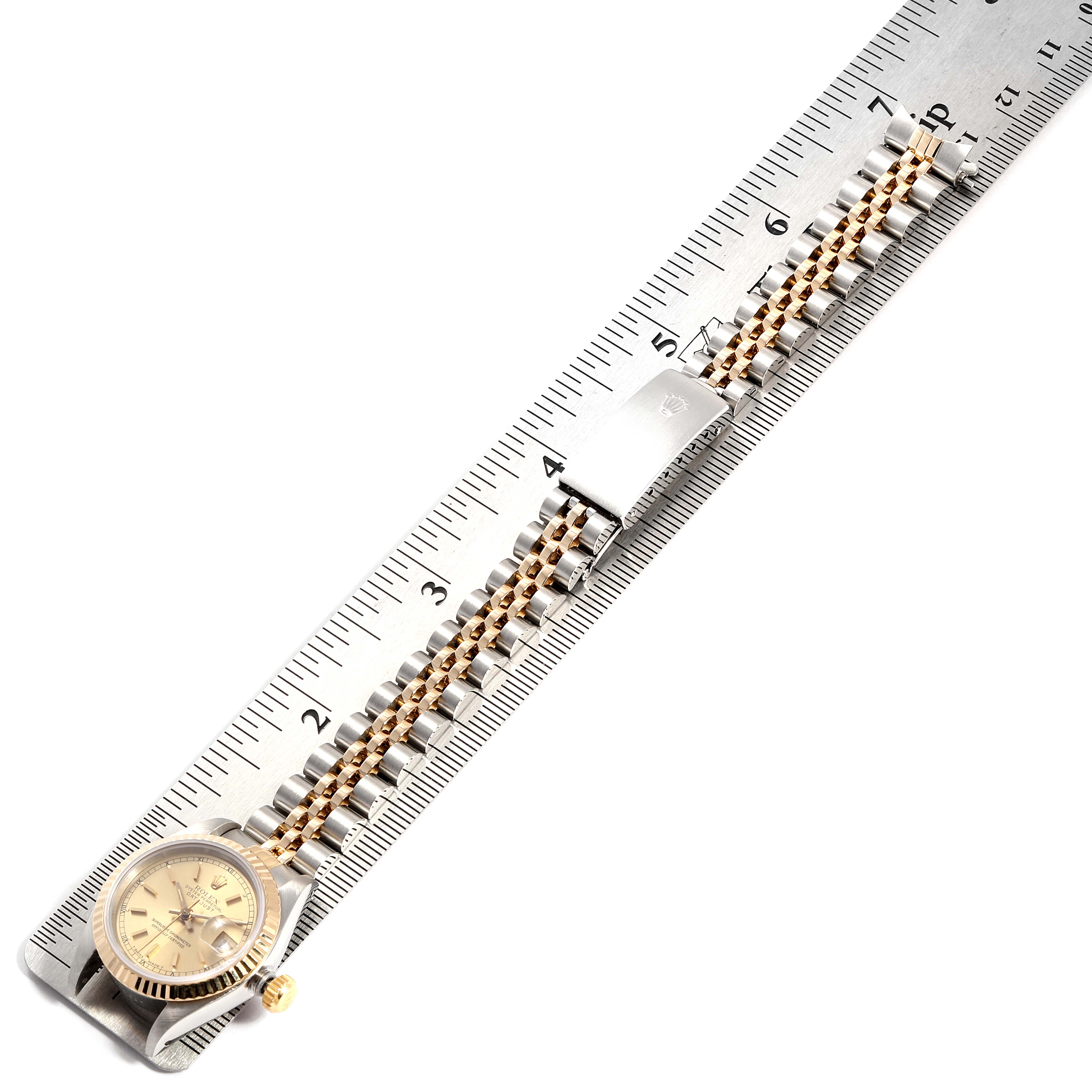 The image shows a Rolex Datejust 69173 Women
s Steel and Gold (two tone) Champagne Dial 69173 Women
s Steel and Gold (two tone) Champagne Dial watch with its strap extended, measured against a metal ruler.