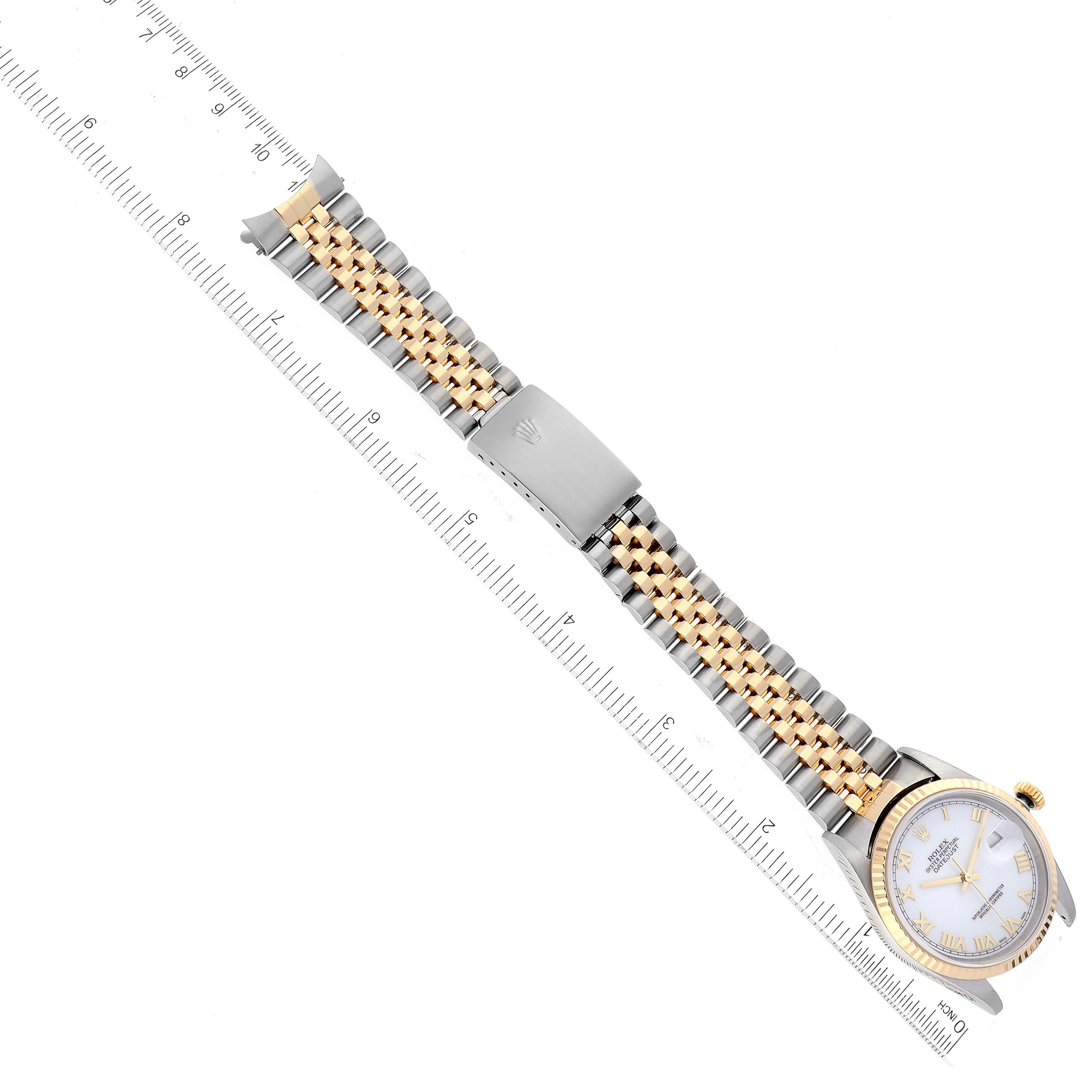 The image shows an overhead view of a Rolex Datejust 16233 Men's Steel and Gold (two tone) White Dial 16233 Men's Steel and Gold (two tone) White Dial watch featuring its dial, bracelet, and clasp, positioned alongside a ruler.
