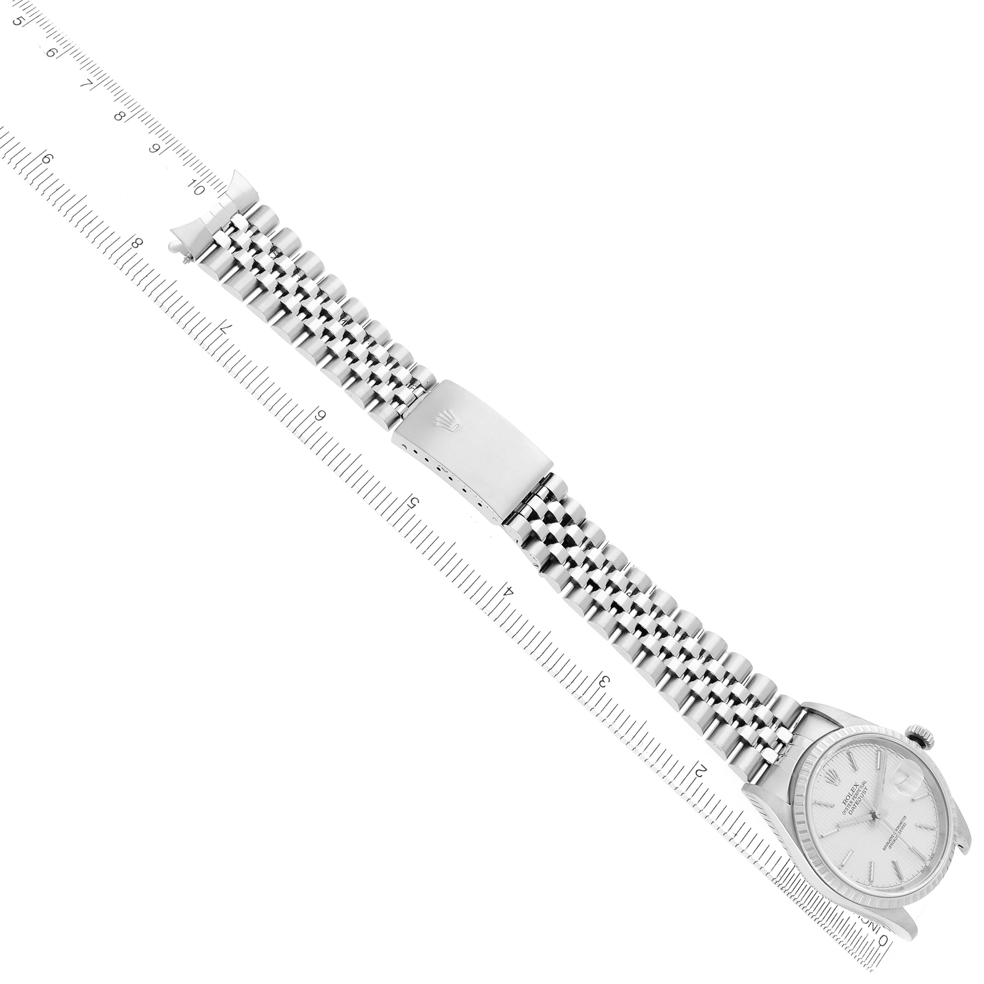 The image shows a Rolex Datejust model 16220 men
s watch from an angled top view, displaying the full bracelet, clasp, and part of the watch face along with a ruler.