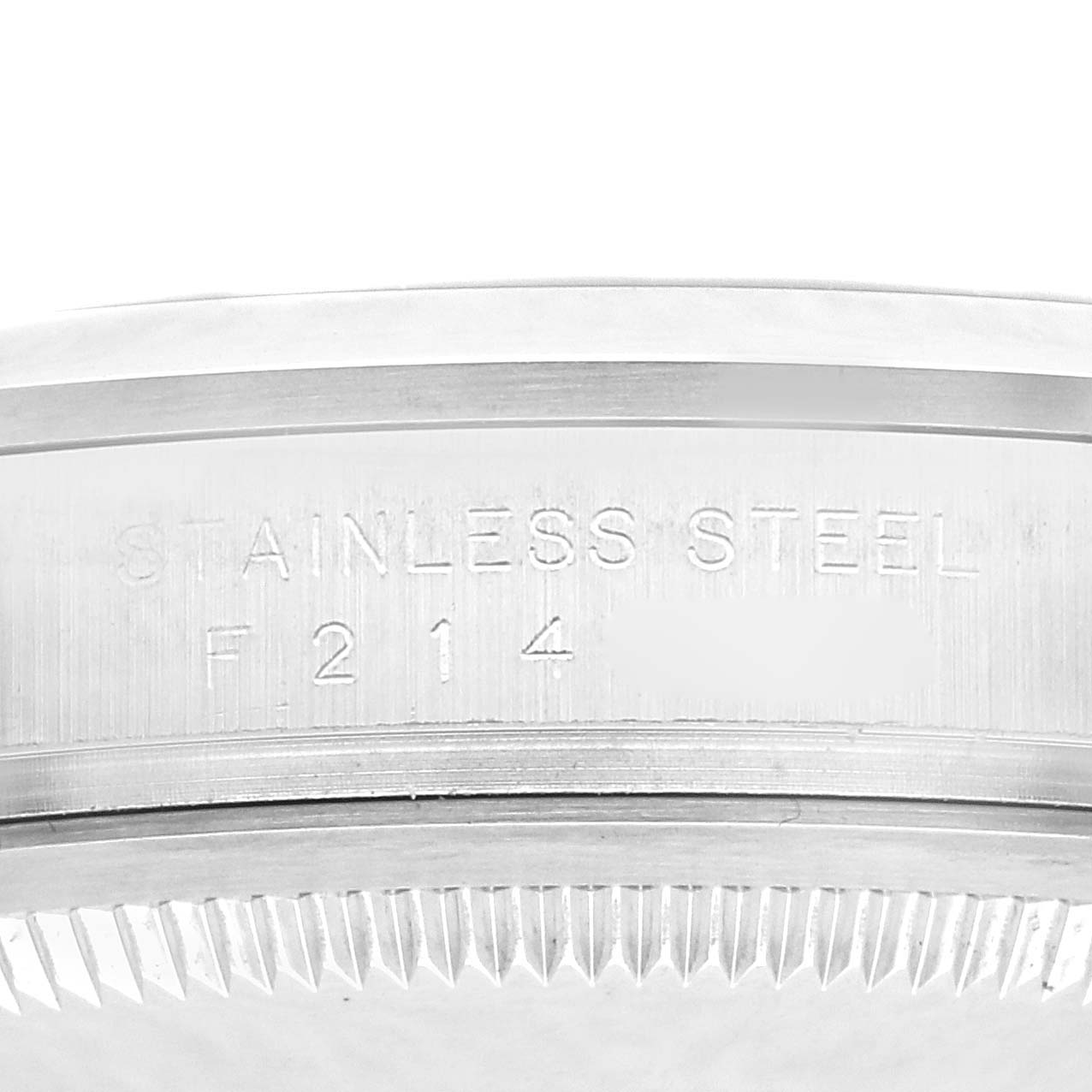 The image shows a close-up of the engraved edge of a Rolex Explorer model 114270, highlighting the "STAINLESS STEEL" inscription and partial serial number.