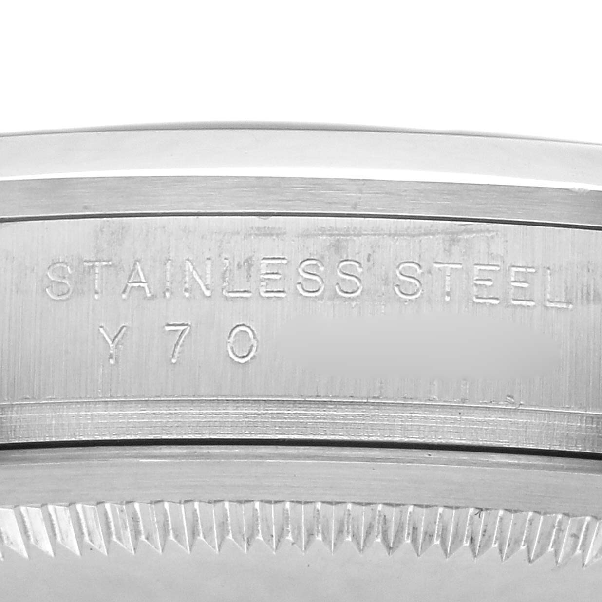 The image shows a close-up of the engraved side of a Rolex Explorer model 114270, highlighting the "STAINLESS STEEL" engraving on the watch case.