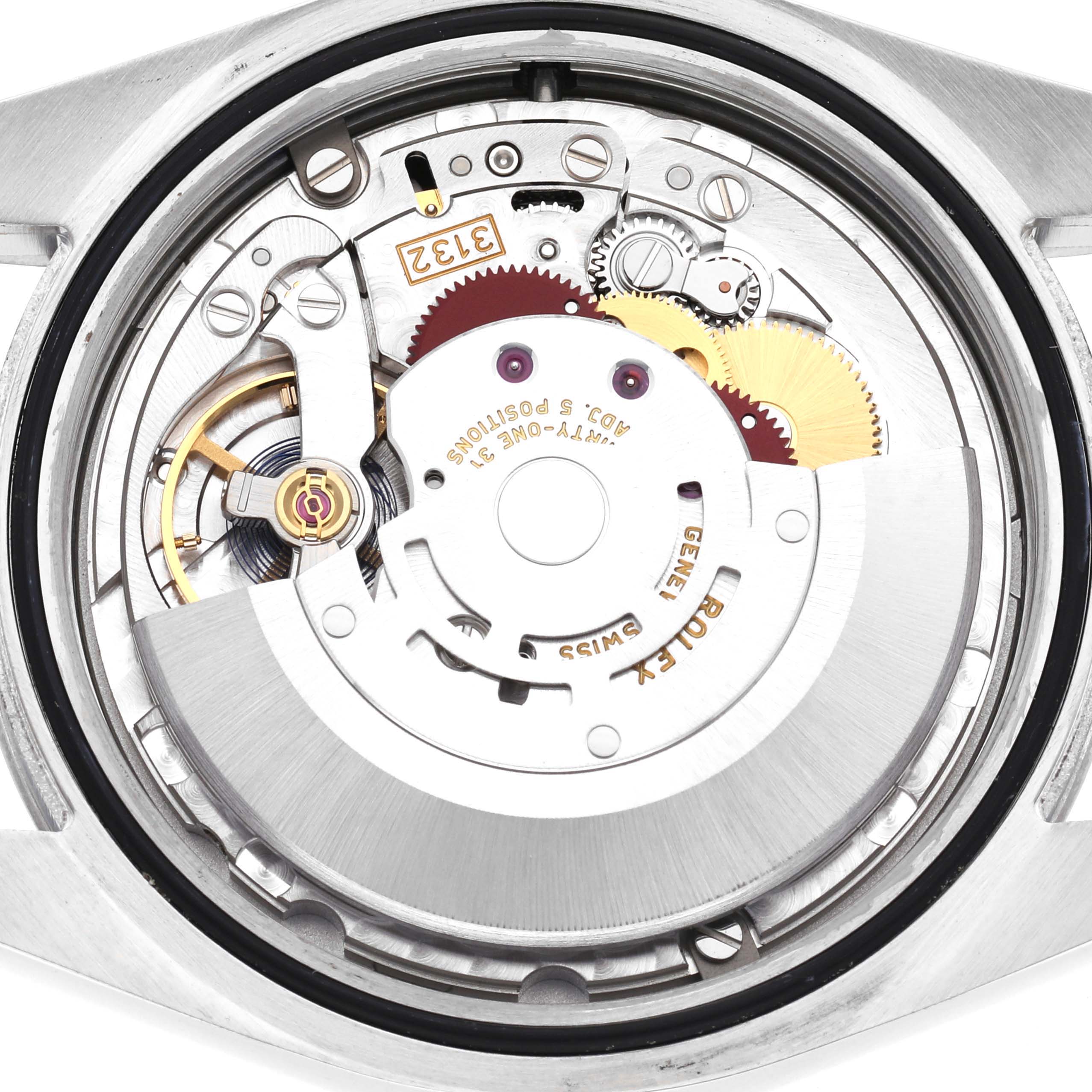The image shows the intricate inner mechanics of a Rolex Oyster Perpetual Model 114300 men's watch from a rear angle, highlighting gears and the rotor.