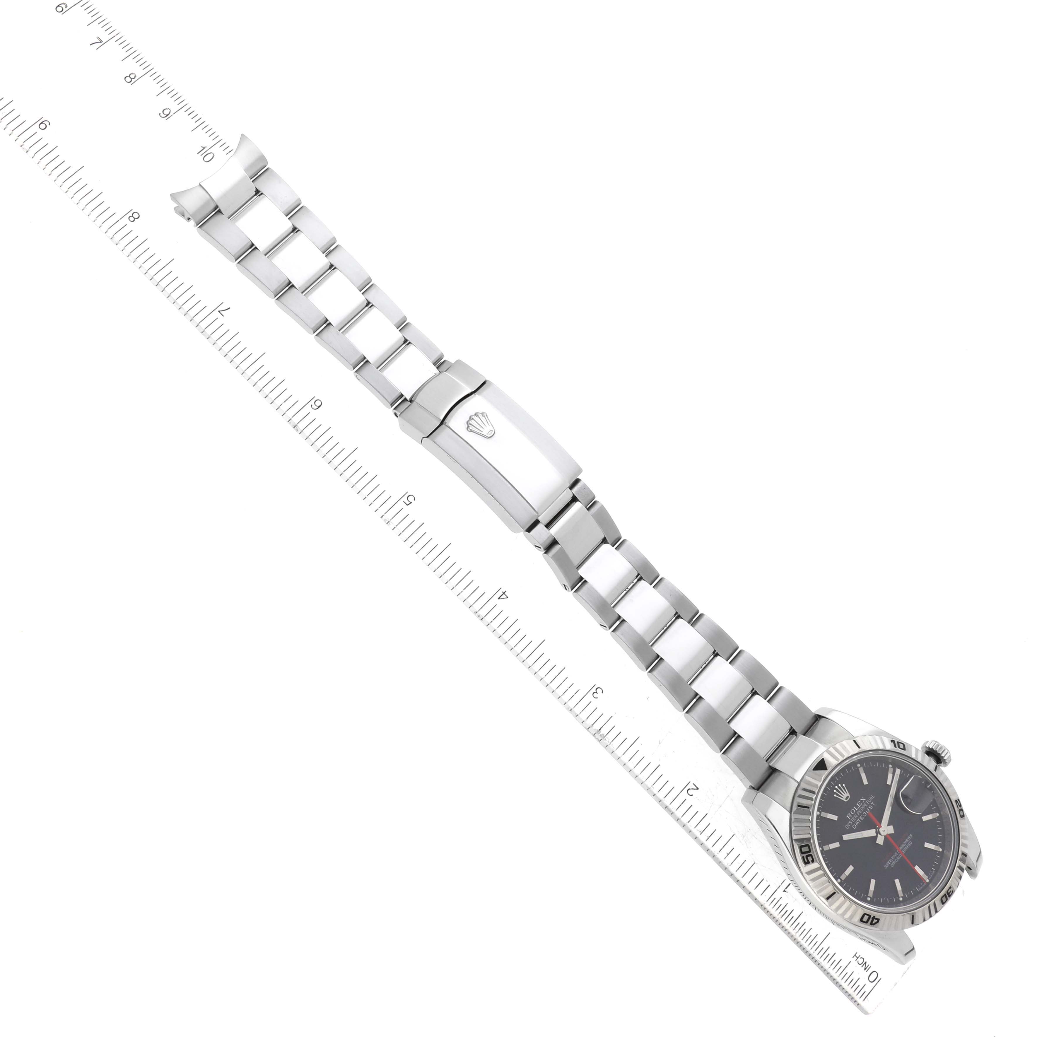 The Rolex Turn-o-Graph 116264 Men's Stainless Steel Black Dial 116264 Men's Stainless Steel Black Dial watch is shown from a slight top and side angle, with the bracelet extended and clasp visible, along with a ruler for scale.