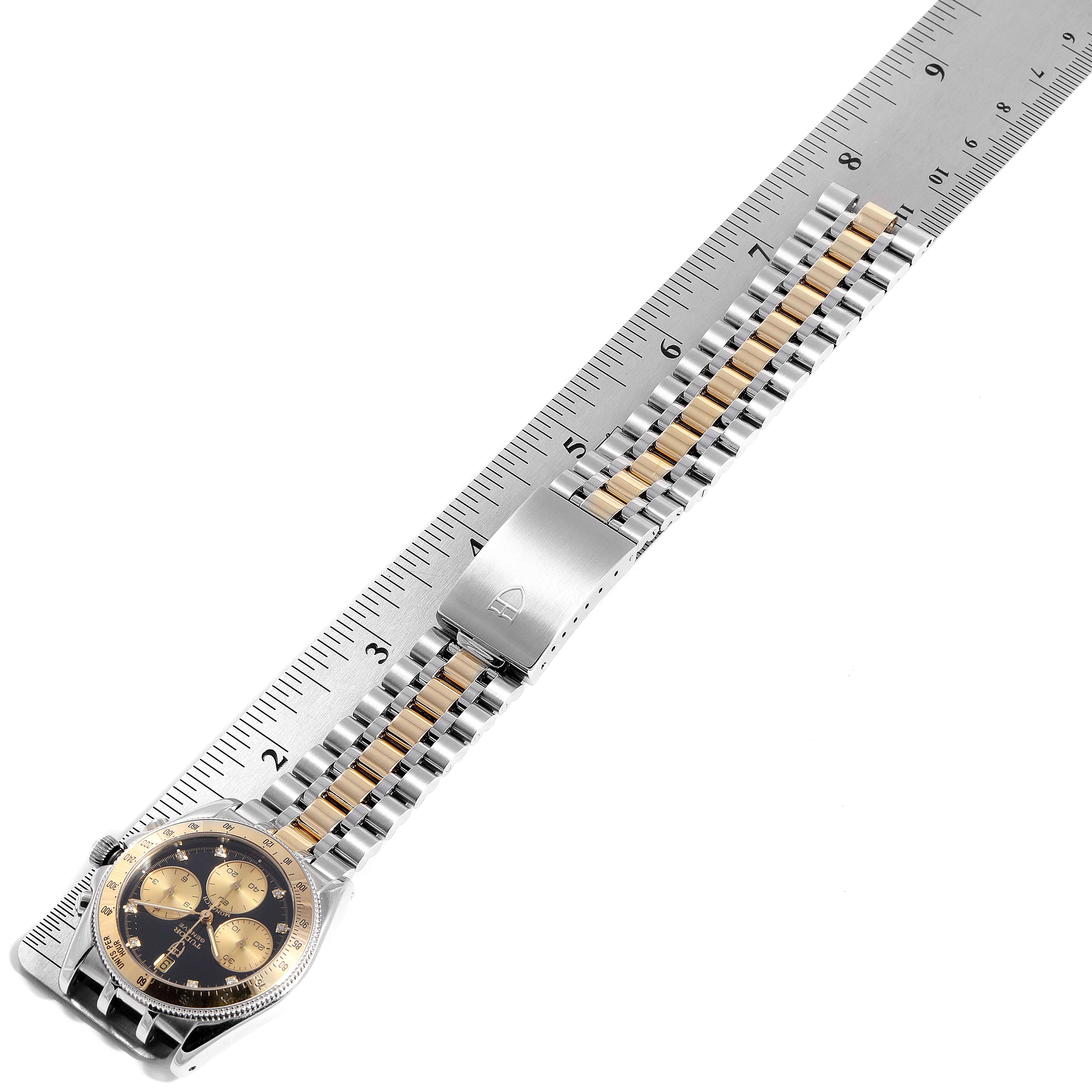 The Tudor Monarch 79180 Men
s Stainless Steel Black Dial 79180 Men
s Stainless Steel Black Dial watch is positioned horizontally with its two-tone bracelet and clasp visible alongside a ruler for measurement.