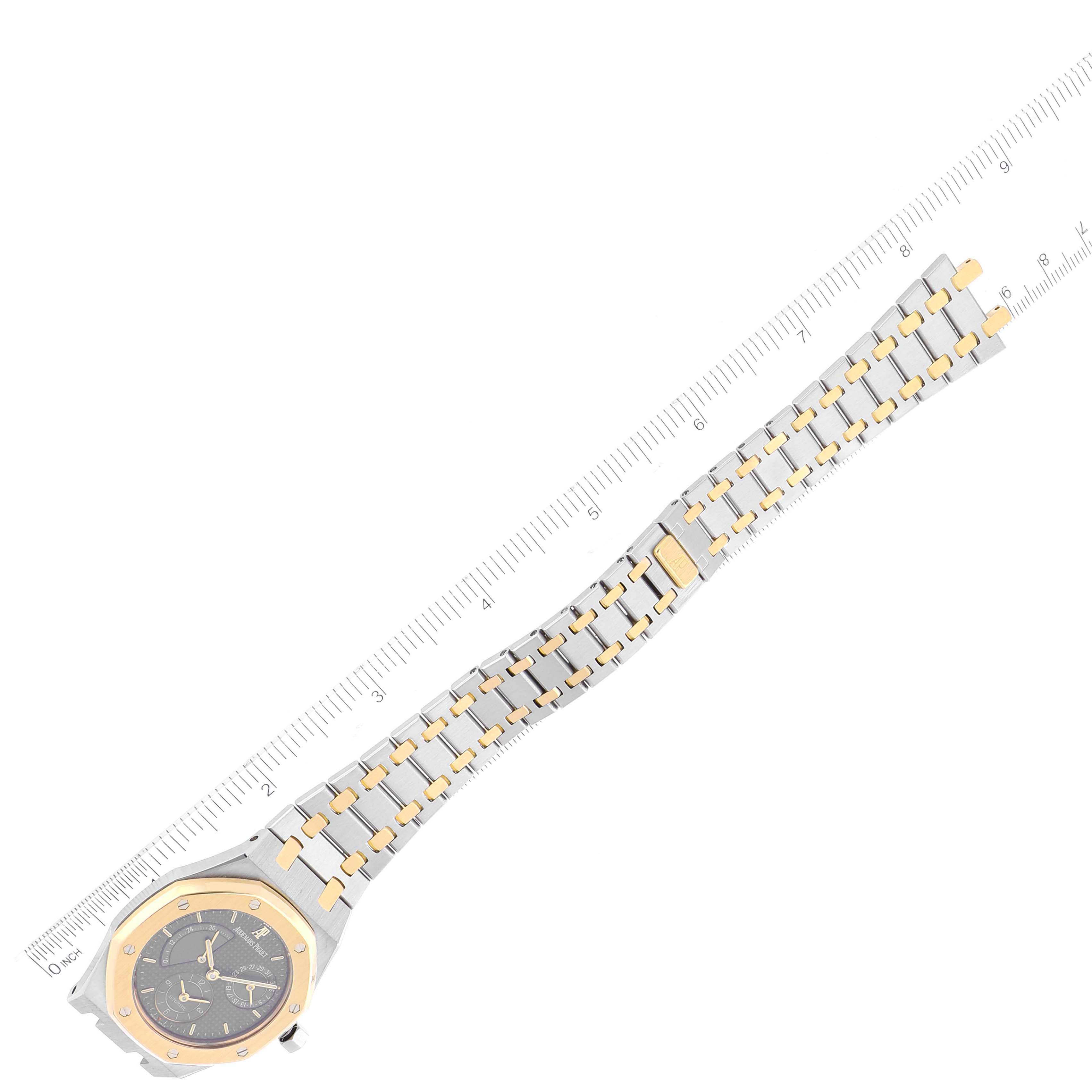 The image shows the Audemars Piguet Royal Oak 25730SA.01.078 Men's Steel and Gold (two tone) Grey Dial 25730SA.01.078 Men's Steel and Gold (two tone) Grey Dial watch from a top-down angle, displaying the face, bezel, and full bracelet alongside a ruler.