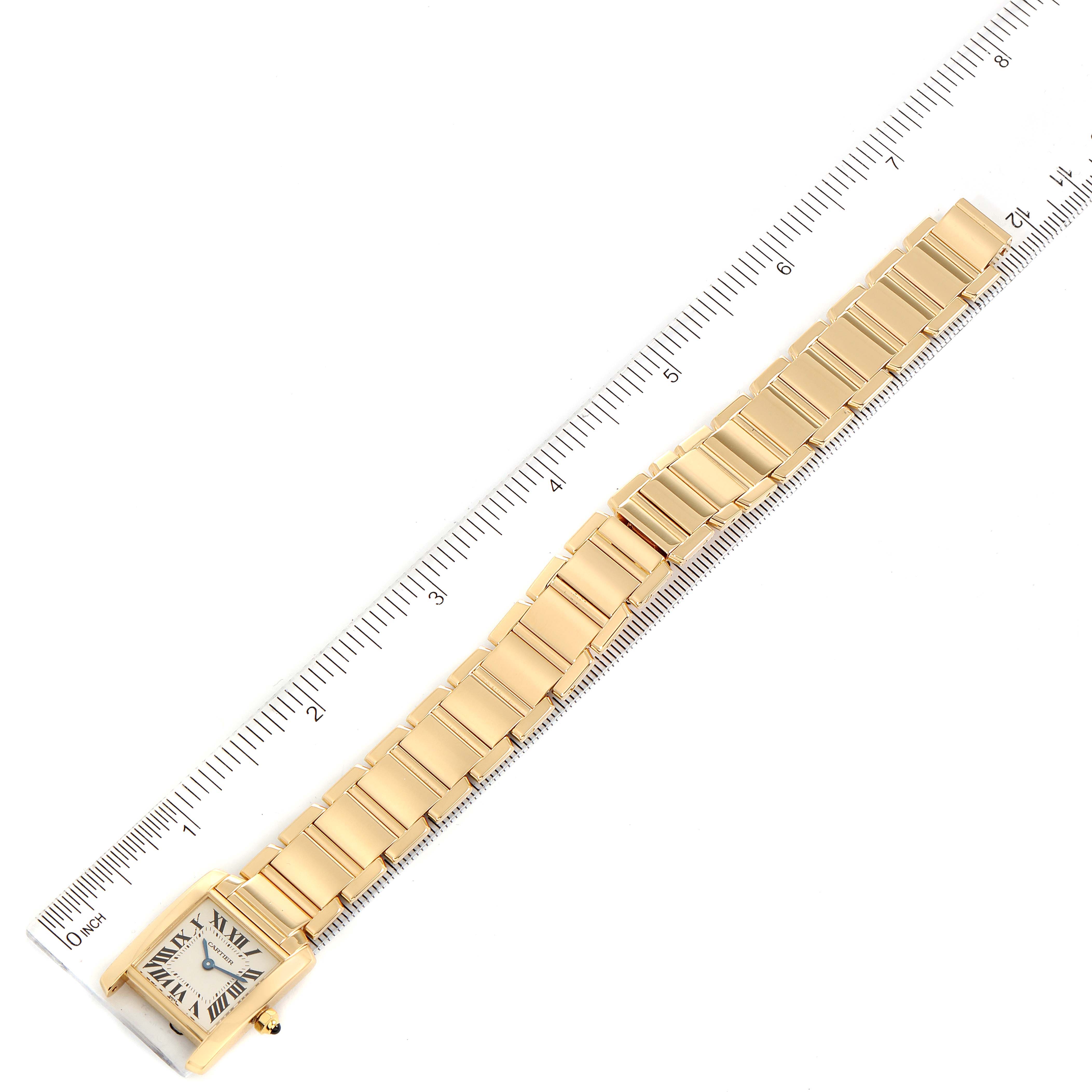This image shows a Cartier Tank Francaise W50002N2 Women's Yellow Gold Silver Dial W50002N2 Women's Yellow Gold Silver Dial watch laid flat beside a ruler, displaying its face and bracelet.