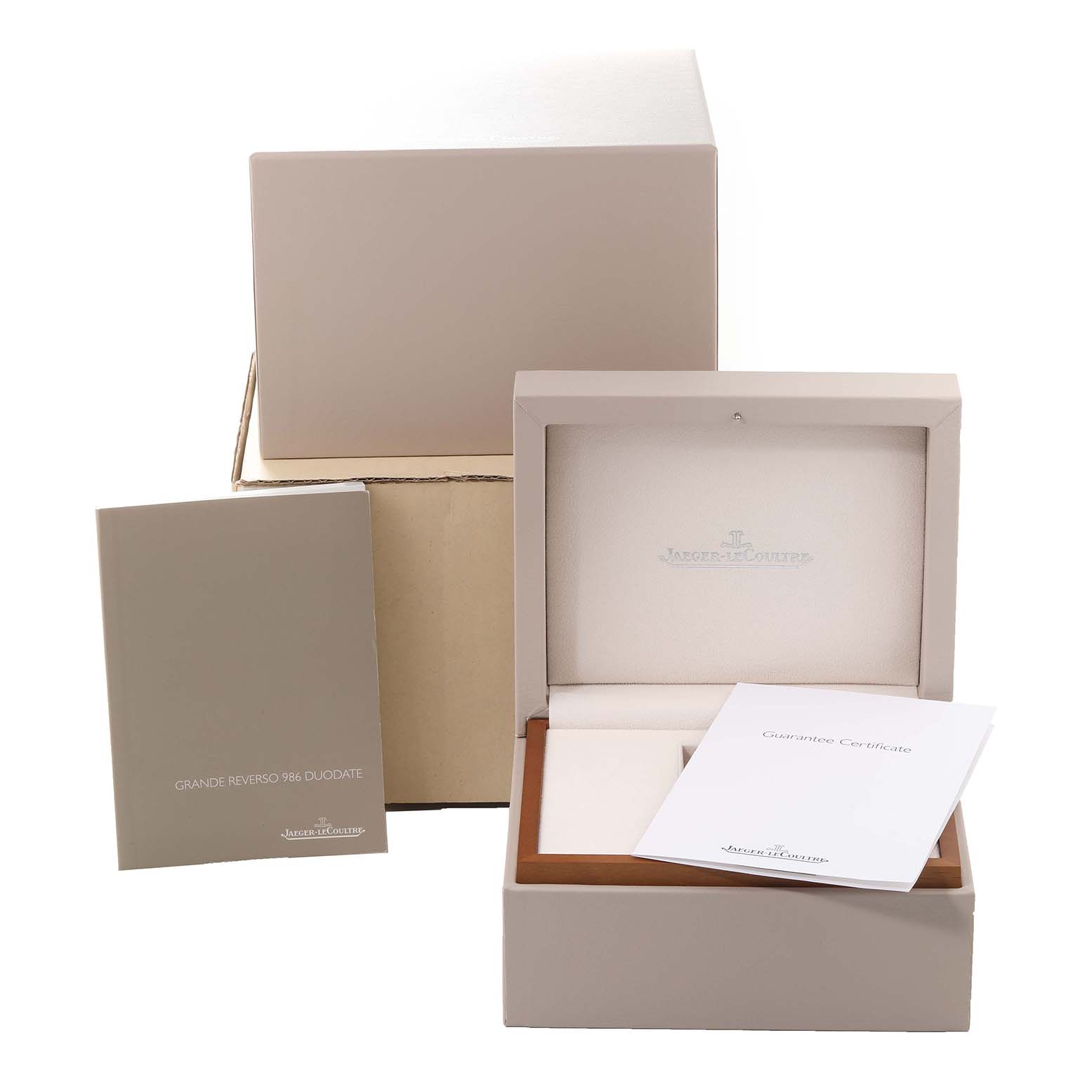 The image shows the packaging and accessories of a Jaeger-LeCoultre Reverso watch, including the box, manual, and guarantee certificate.