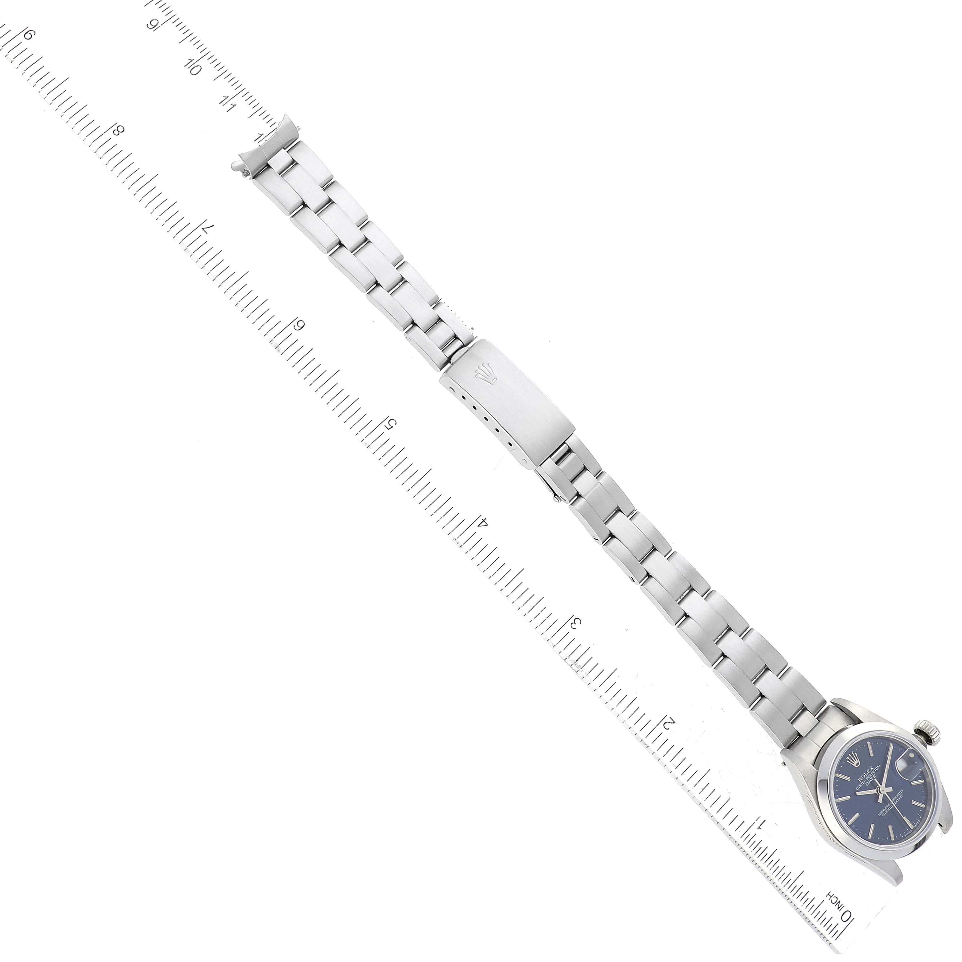 The image shows a top-down view of a Rolex Date 69160 Women's Stainless Steel Blue Dial 69160 Women's Stainless Steel Blue Dial model watch with its bracelet fully extended next to a ruler.