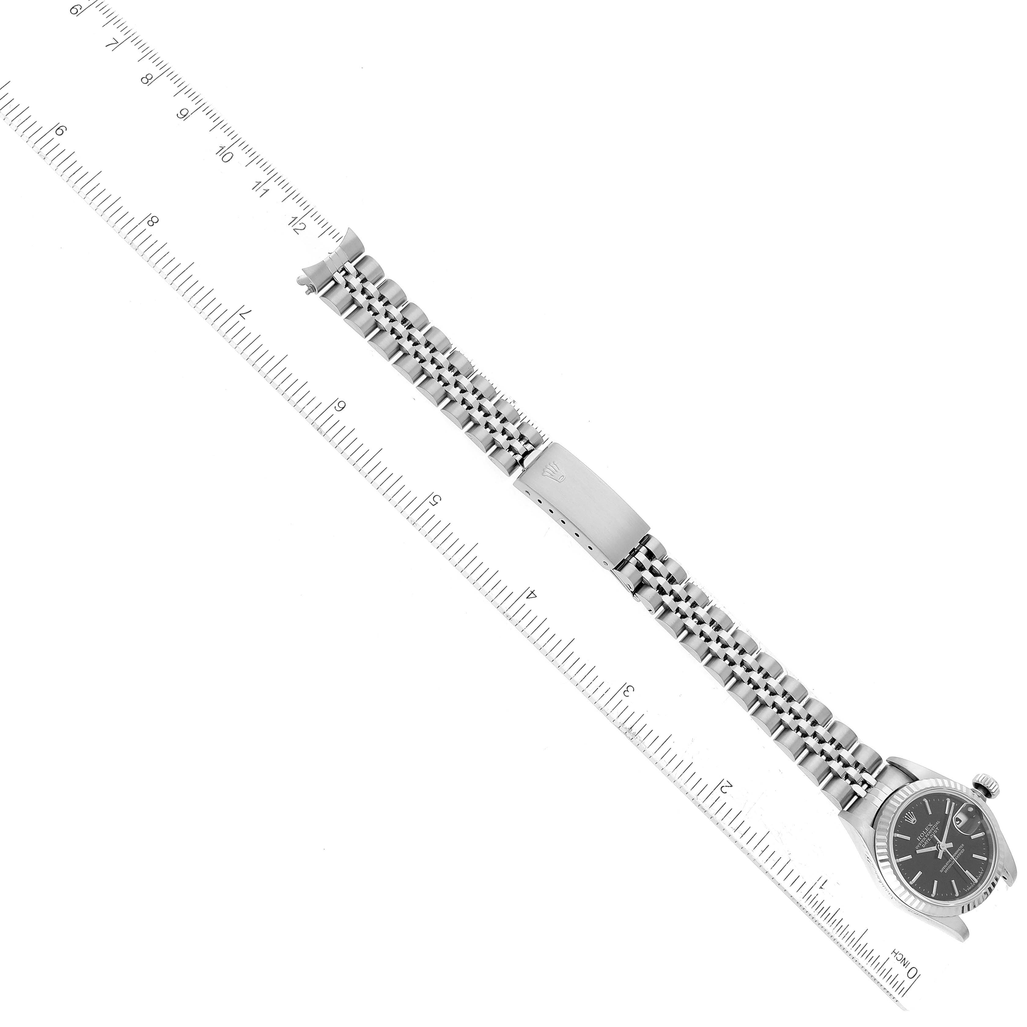 The image shows a top-down view of a Rolex Datejust 69174 Women's Stainless Steel Black Dial 69174 Women's Stainless Steel Black Dial watch, highlighting the bracelet and clasp along with a ruler for scale.