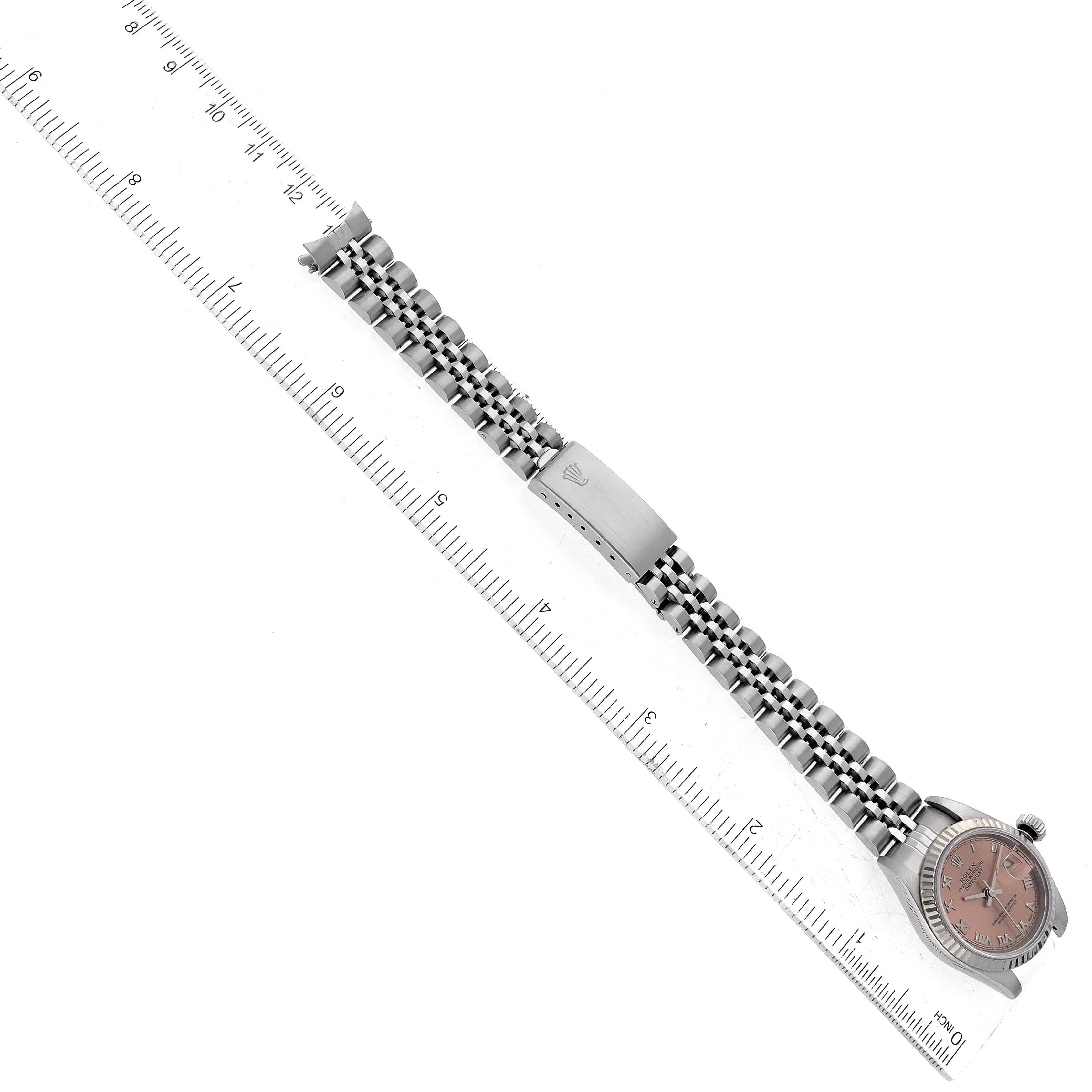 This is a top-down view of a Rolex Datejust 69174 Women's Stainless Steel Pink Dial 69174 Women's Stainless Steel Pink Dial watch alongside a ruler, showing the face and metal bracelet.