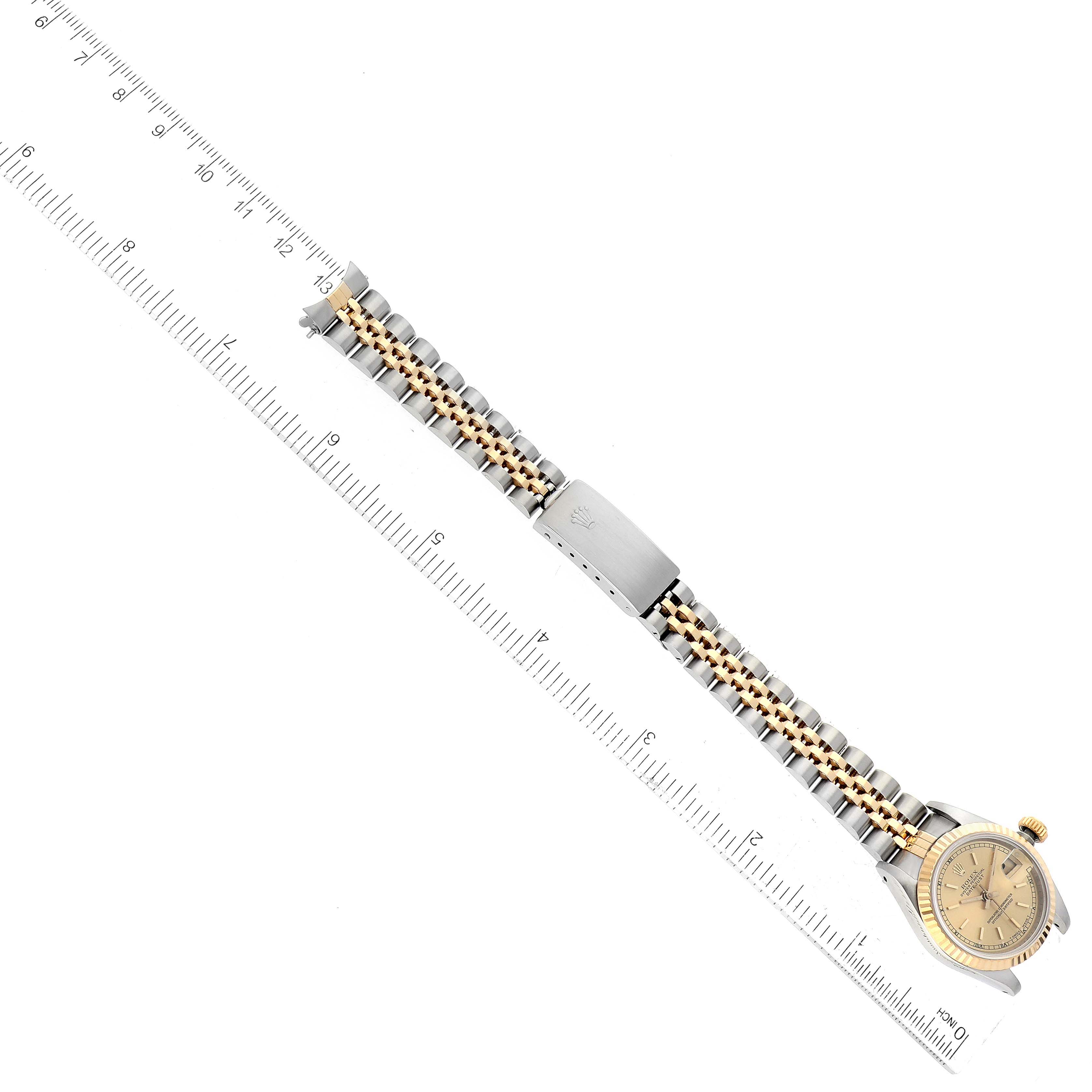 This image shows a Rolex Datejust 69173 Women's Steel and Gold (two tone) Champagne Dial 69173 Women's Steel and Gold (two tone) Champagne Dial watch displayed diagonally with its full bracelet and clasp on a ruler for scale.