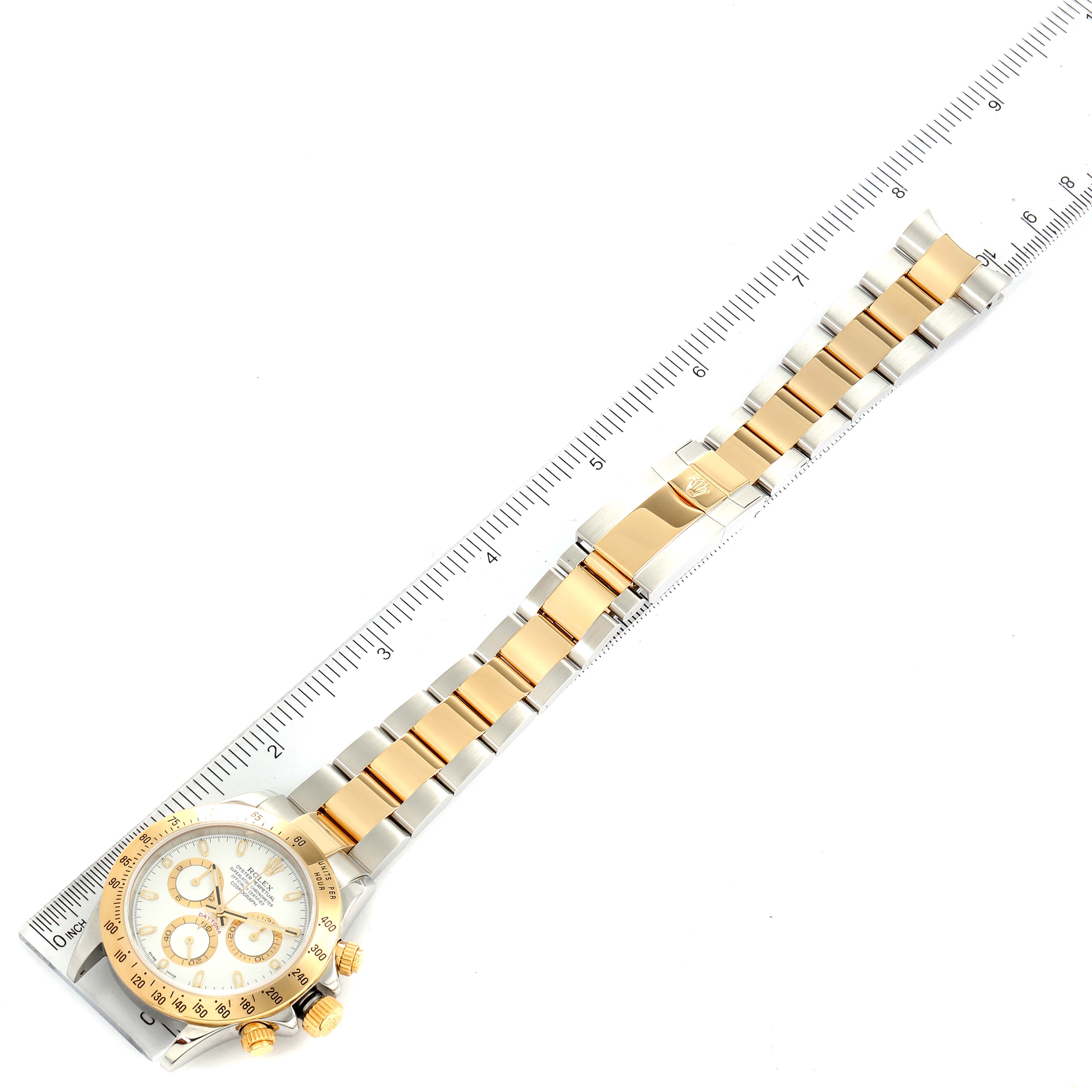 The image shows a top-down view of a Rolex Daytona 116523 Men's Steel and Gold (two tone) White Dial 116523 Men's Steel and Gold (two tone) White Dial watch, including the dial and bracelet, placed next to a ruler for scale.
