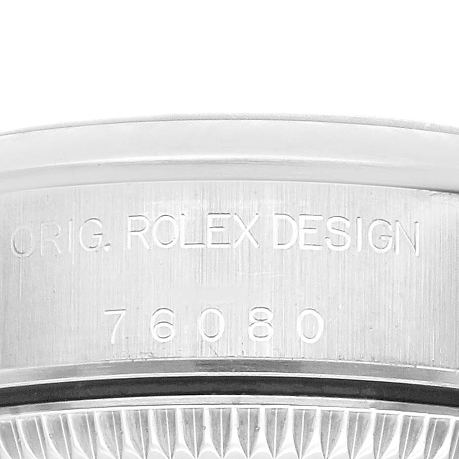 The image shows a close-up of the side of the bezel and casing of a Rolex Oyster Perpetual 76080 Women's Stainless Steel Black Dial 76080 Women's Stainless Steel Black Dial, featuring the model number and "ROLEX DESIGN" engraving.
