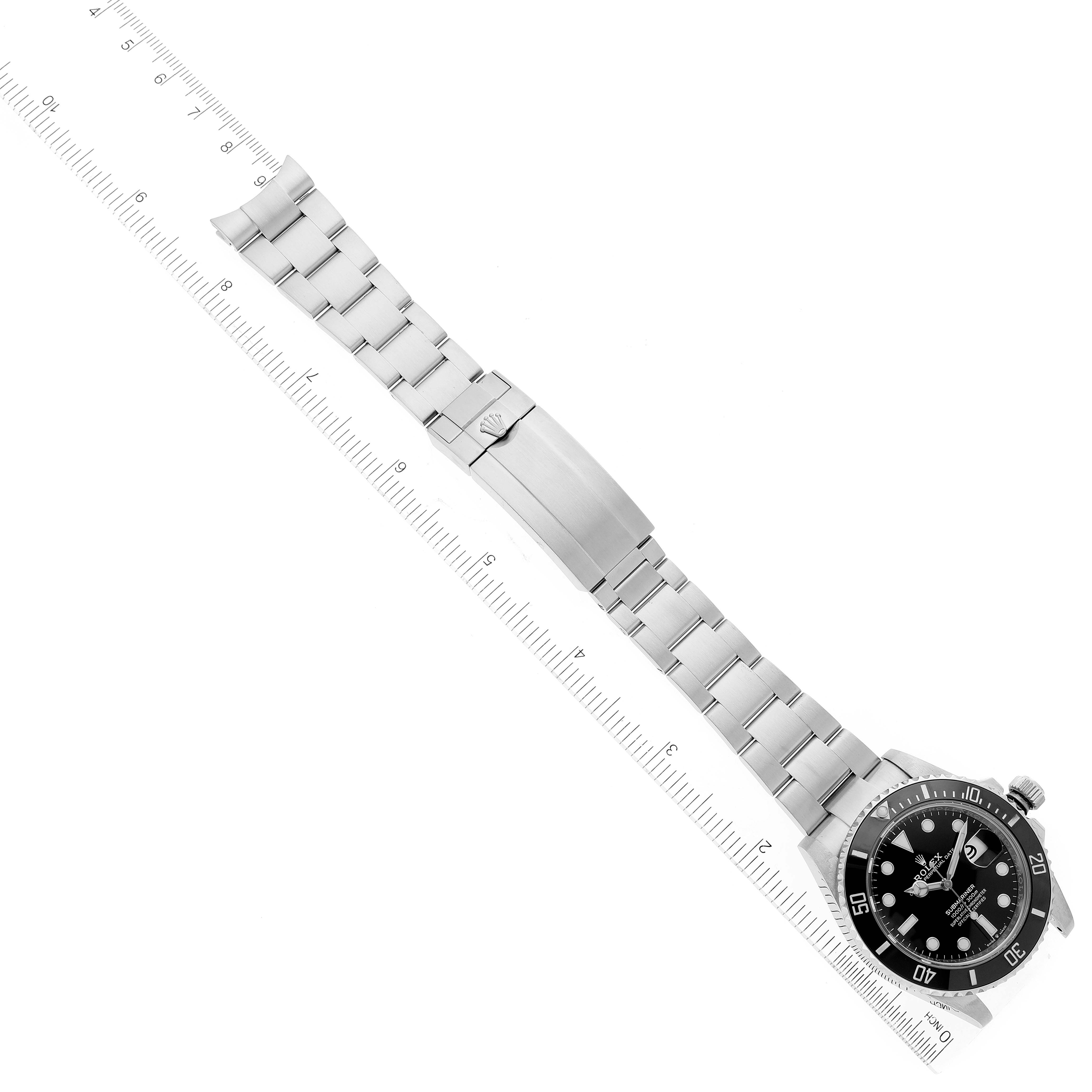 The image shows a top-down view of a Rolex Submariner 126610 Men
s Stainless Steel Black Dial 126610 Men
s Stainless Steel Black Dial watch with its full metal bracelet and clasp extended alongside a ruler.
