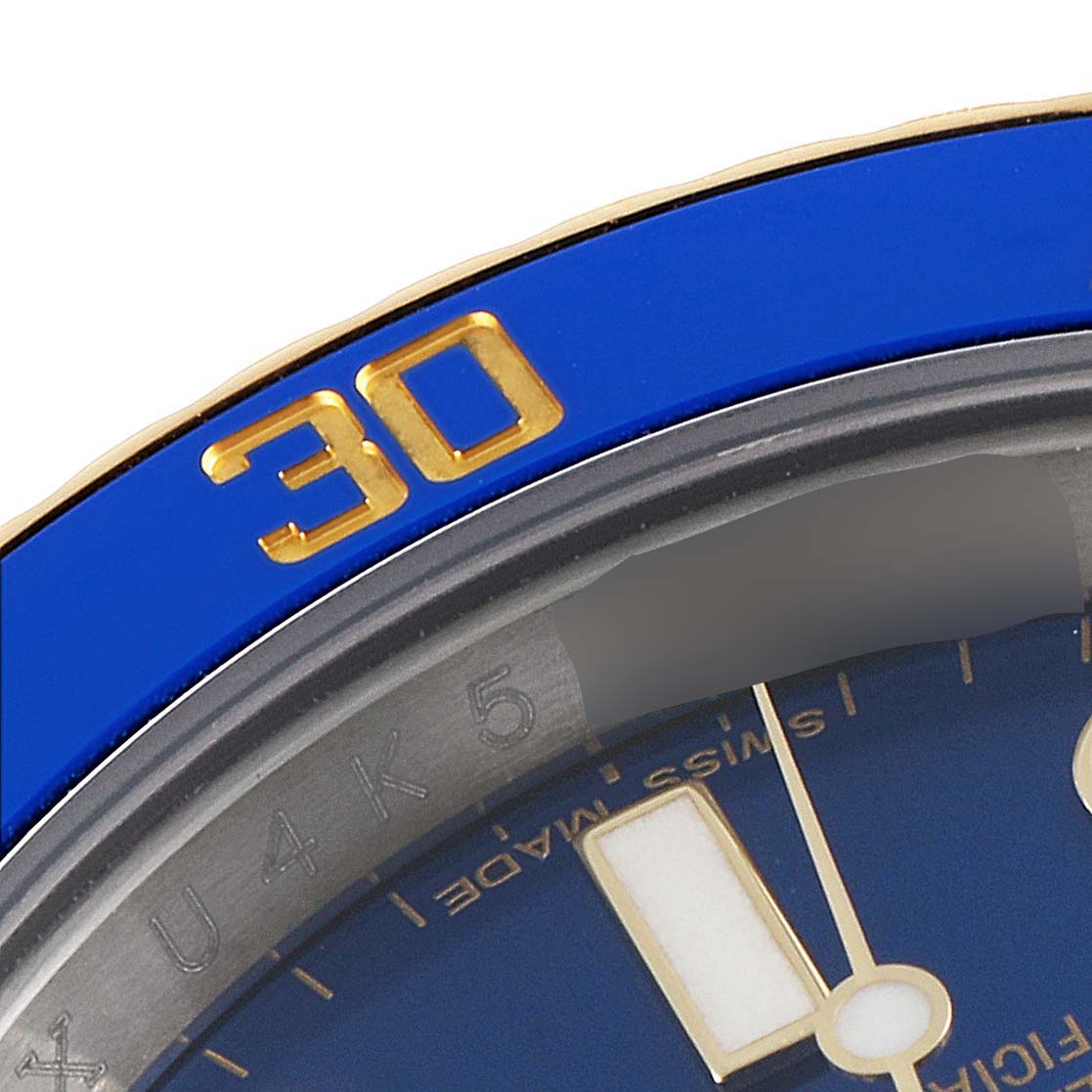 This close-up angle of the Rolex Submariner 116613 Men
s Steel and Gold (two tone) Blue Dial 116613 Men
s Steel and Gold (two tone) Blue Dial watch shows the blue bezel and part of the dial with a yellow-gold 30-minute marker.