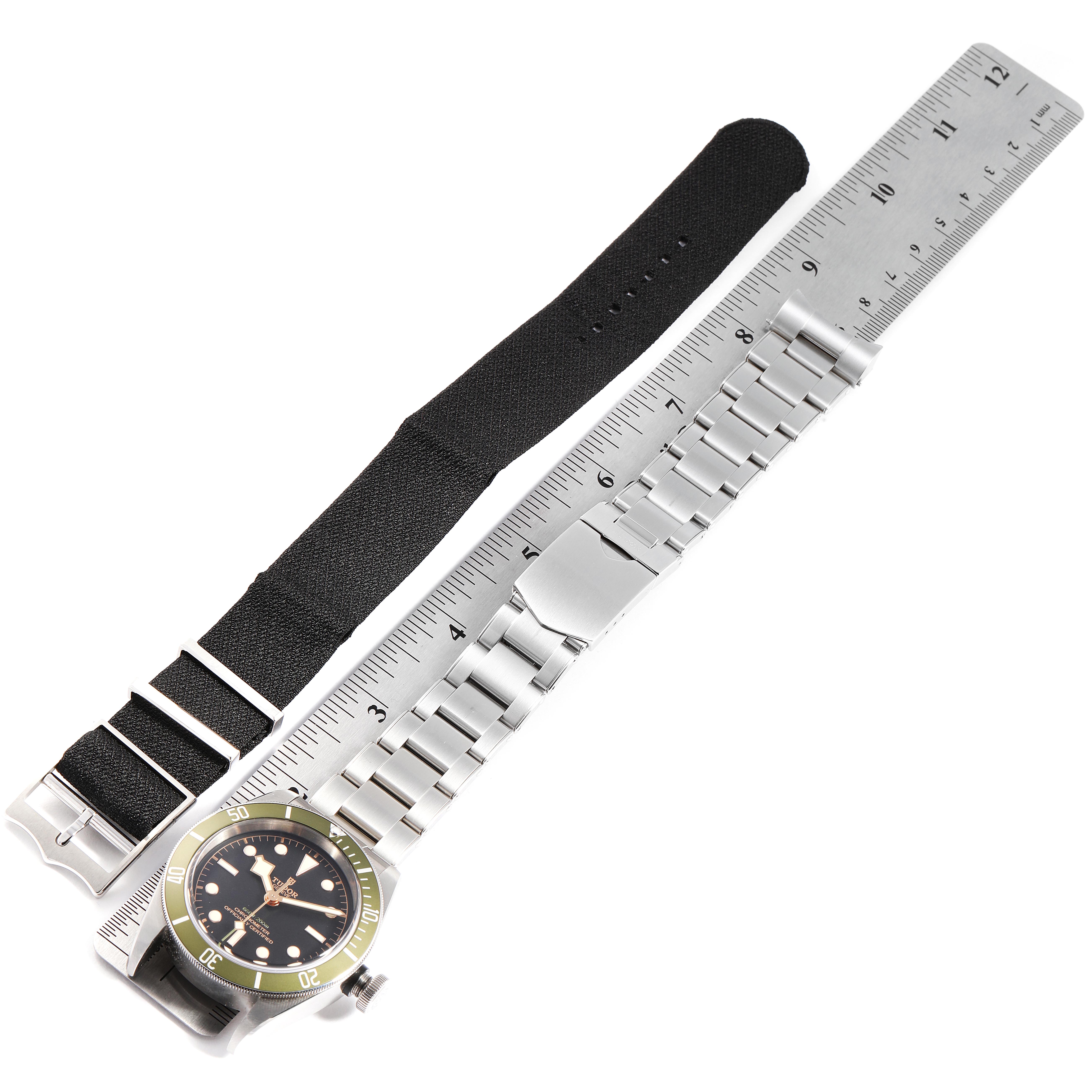 The image shows the Heritage Black Bay watch by Tudor with a metal bracelet and black strap, lying next to a ruler for scale.