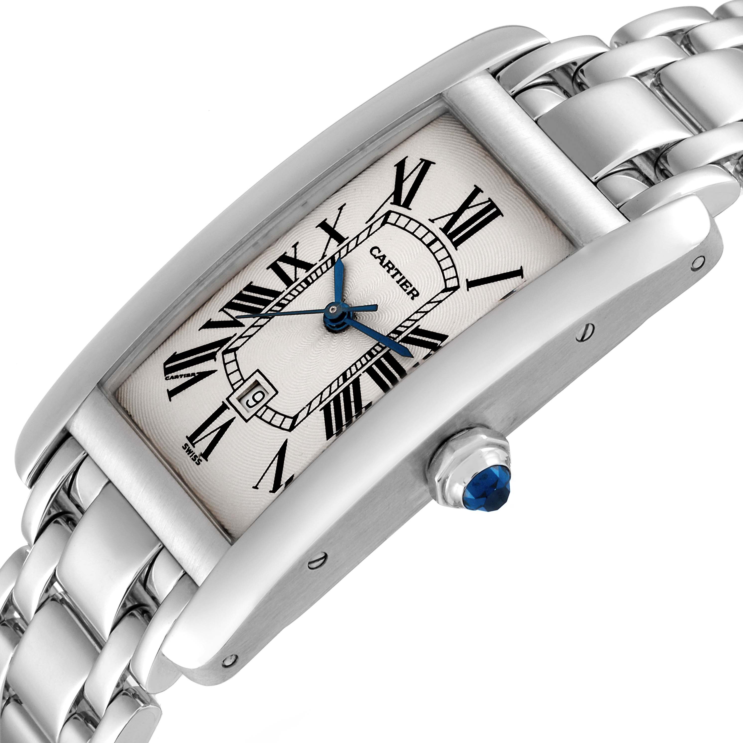 The Cartier Tank Americaine W26036L1 Women's White Gold Silver Dial W26036L1 Women's White Gold Silver Dial watch is shown at an angle displaying its Roman numeral dial, blue hands, crown, and metal bracelet.