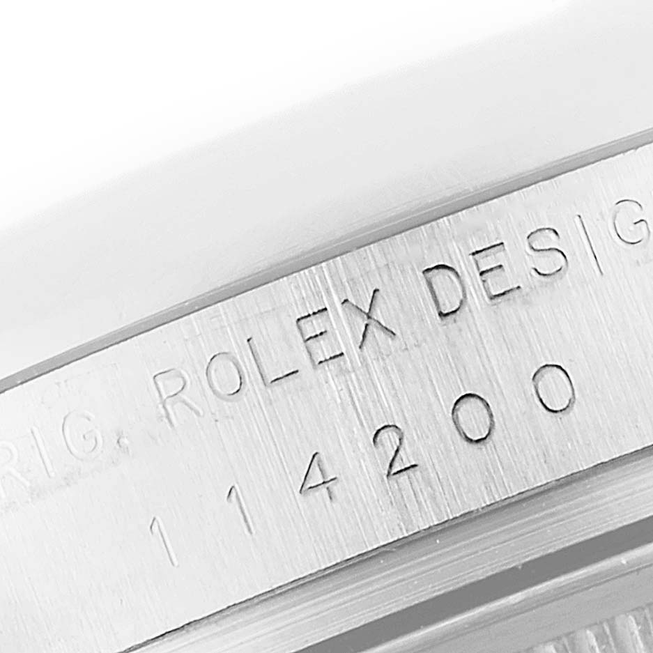 The image shows a close-up of the model number and "Rolex Design" engraving on a Rolex Air-King 114200 Men's Stainless Steel White Dial 114200 Men's Stainless Steel White Dial watch case.
