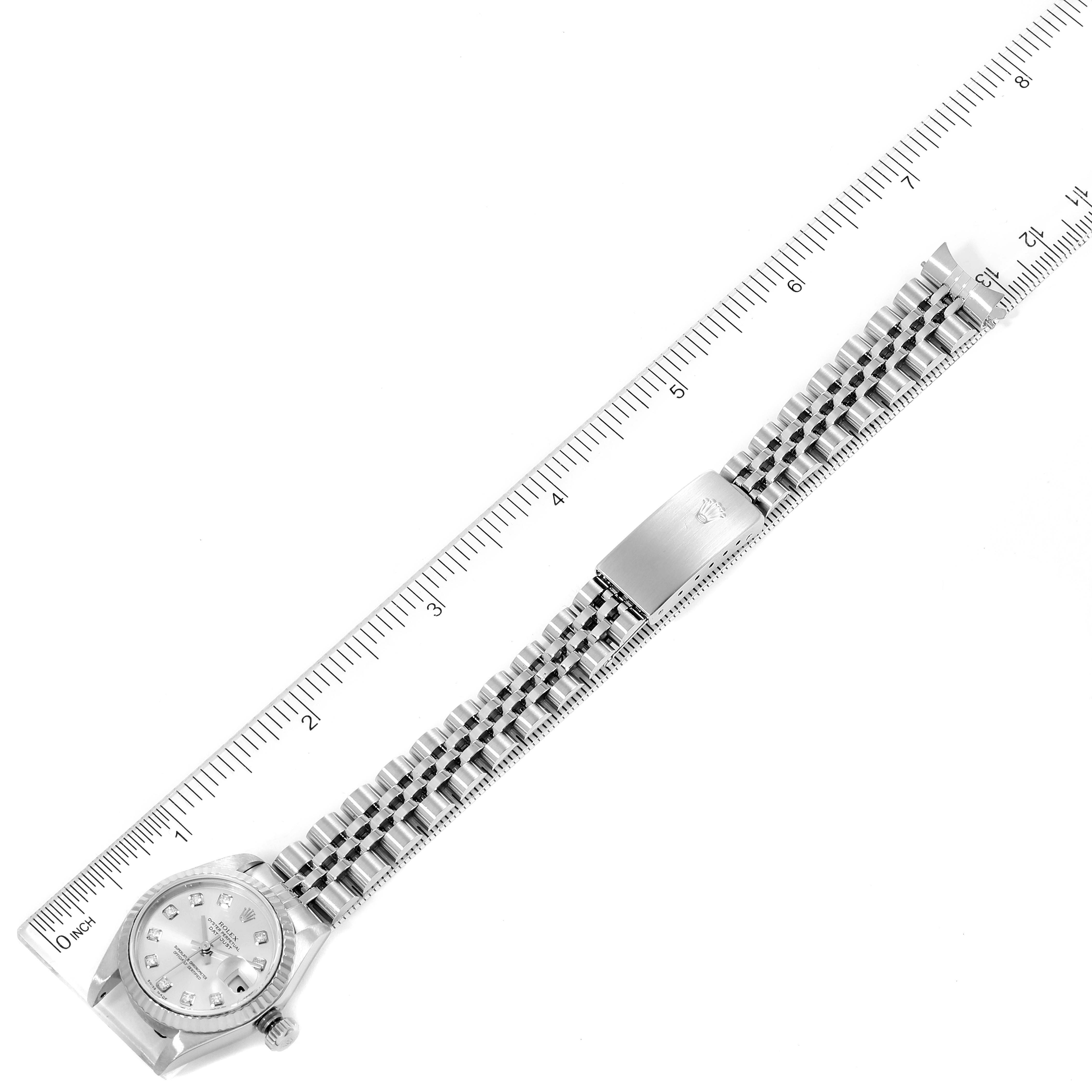 The image shows a Rolex Datejust 79174 Women
s Stainless Steel Silver Dial 79174 Women
s Stainless Steel Silver Dial watch laid flat next to a ruler, displaying the entire watch including the dial, bracelet, and clasp.