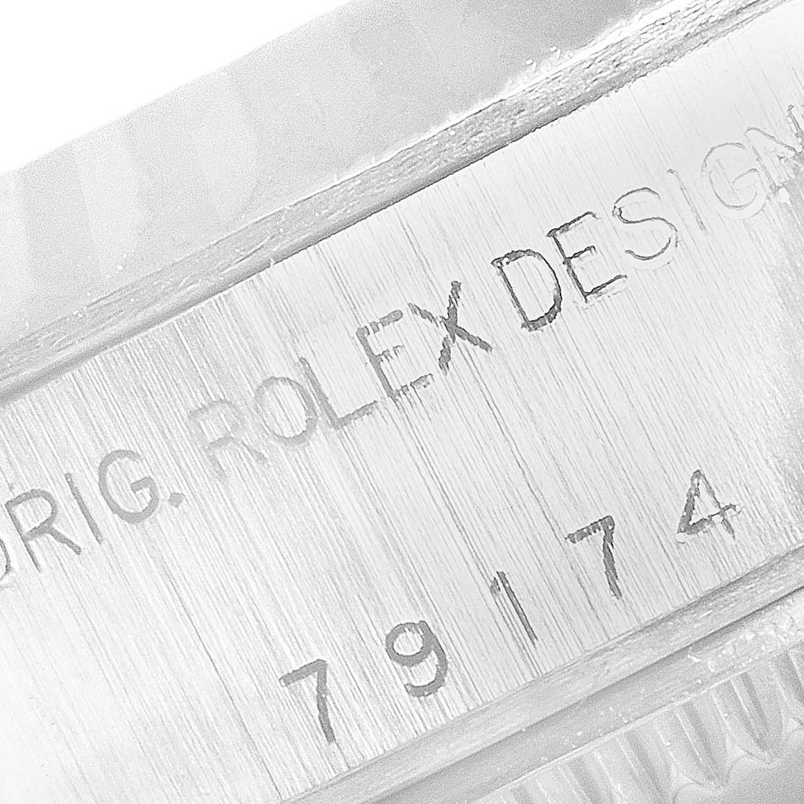 This close-up image shows the engraved serial number and "ORIG. ROLEX DESIGN" text on a Rolex Datejust 79174 Women
s Stainless Steel Silver Dial 79174 Women
s Stainless Steel Silver Dial model.