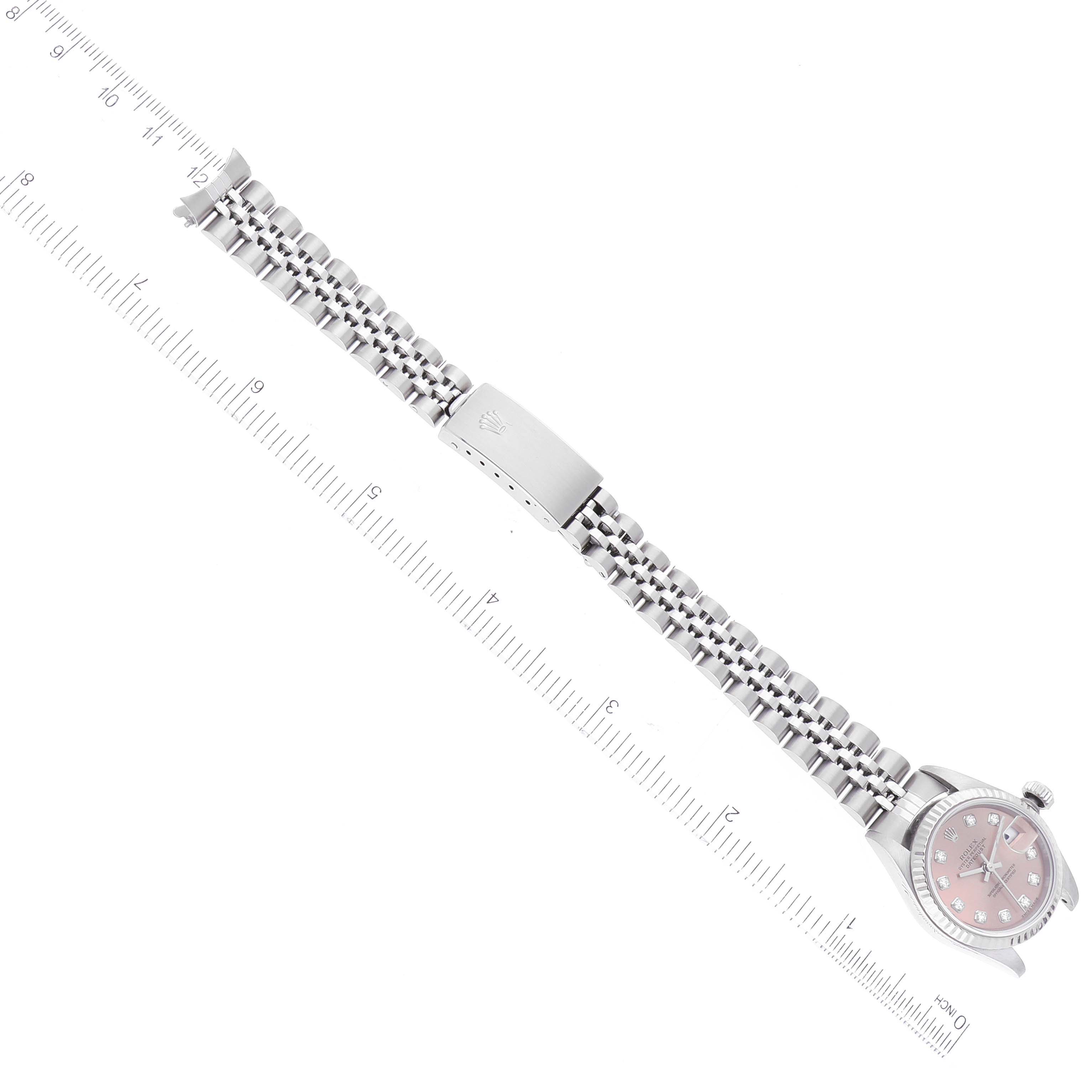 This image shows a top-down view of a Rolex Datejust 79174 Women's Stainless Steel Pink Dial 79174 Women's Stainless Steel Pink Dial watch with its full bracelet laid flat next to a ruler.