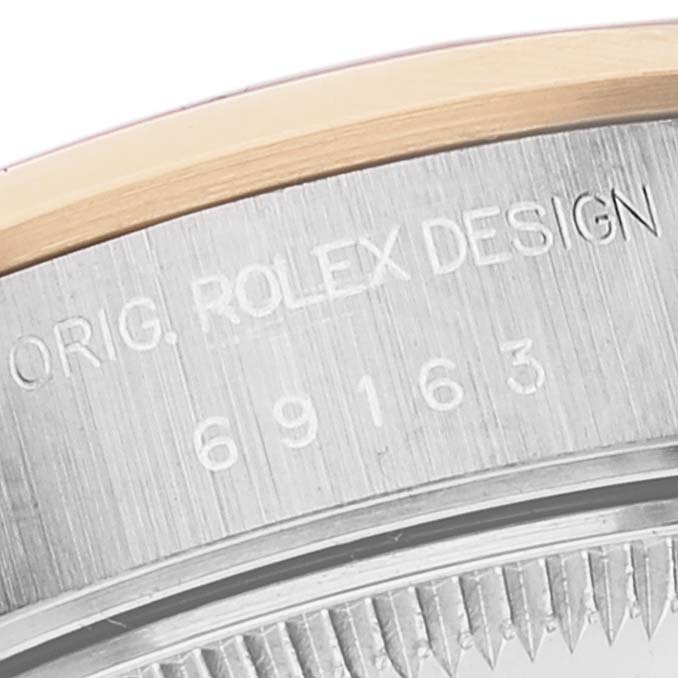 Close-up of the side of a Rolex Datejust 69163 Women
s Steel and Gold (two tone) Blue Dial 69163 Women
s Steel and Gold (two tone) Blue Dial watch, showing engraved text and part of the bezel.