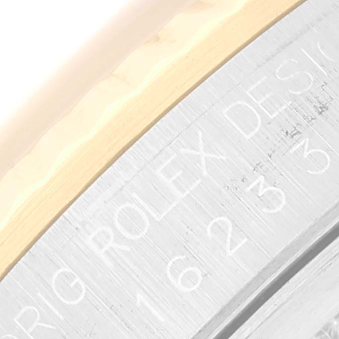 This image shows a close-up of the side of the bezel and case of a Rolex Datejust 16233 Men's Steel and Gold (two tone) Champagne Dial 16233 Men's Steel and Gold (two tone) Champagne Dial watch, highlighting the engraved "ROLEX DESIGN" text.