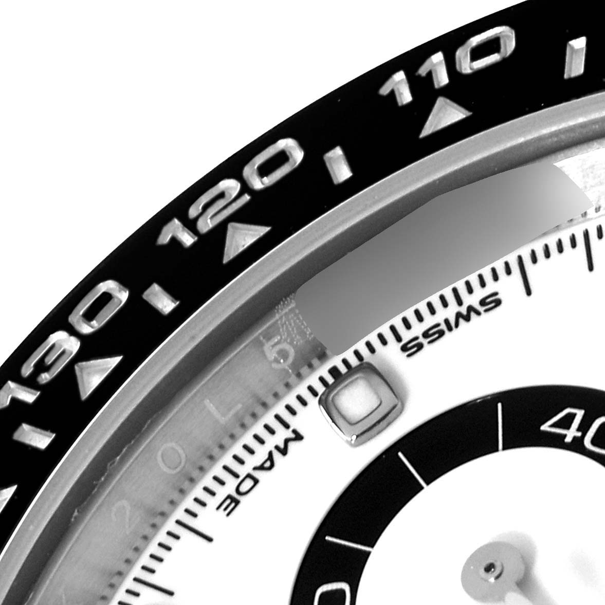 A close-up of the bezel and part of the dial of a Rolex Daytona 116500 Men's Stainless Steel White Dial 116500 Men's Stainless Steel White Dial watch, showing the tachymeter scale and some markers.