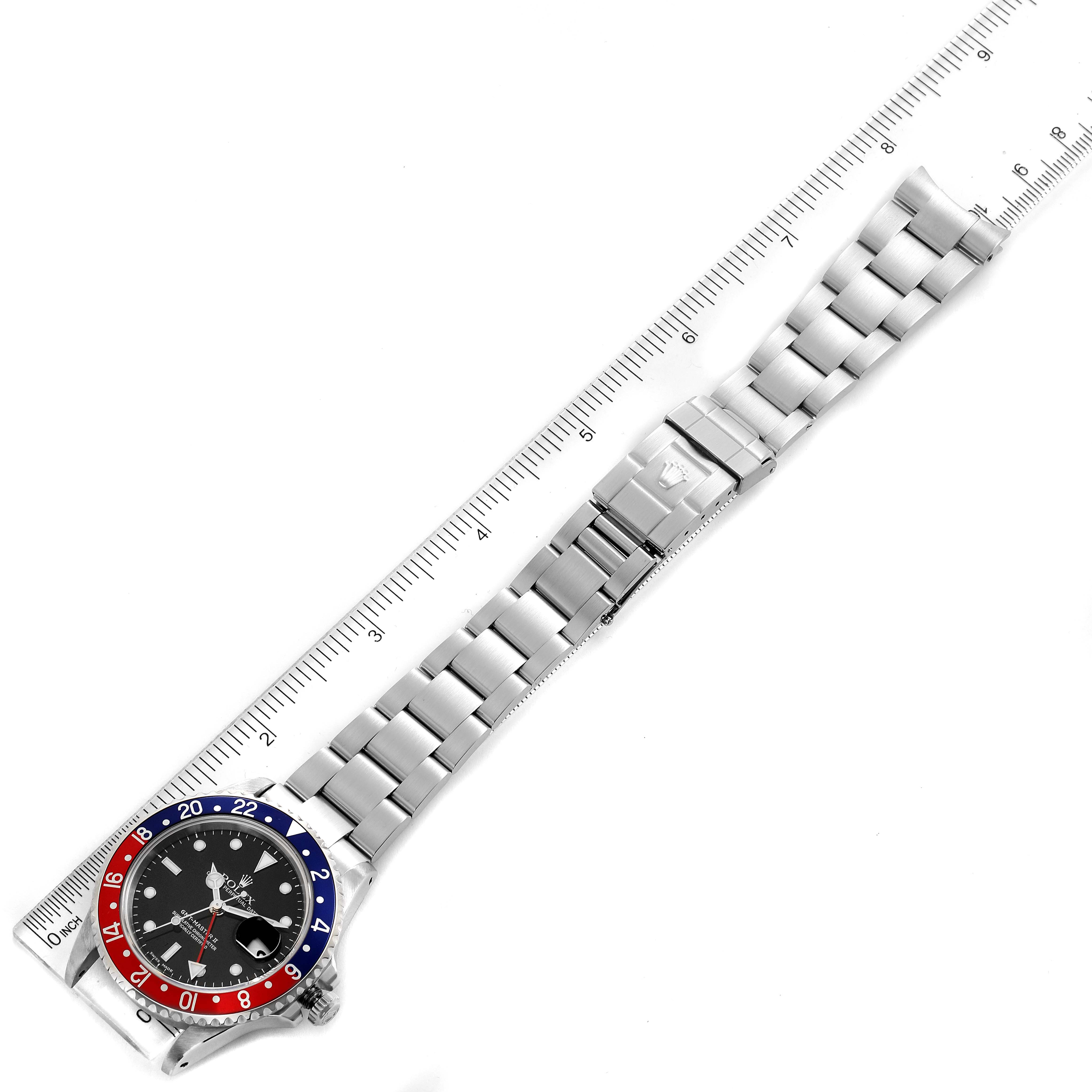The Rolex GMT-Master 16710 Men's Stainless Steel Black Dial 16710 Men's Stainless Steel Black Dial watch is shown from a top-down angle, displaying the face, bezel, and full metal bracelet placed on a measuring ruler.