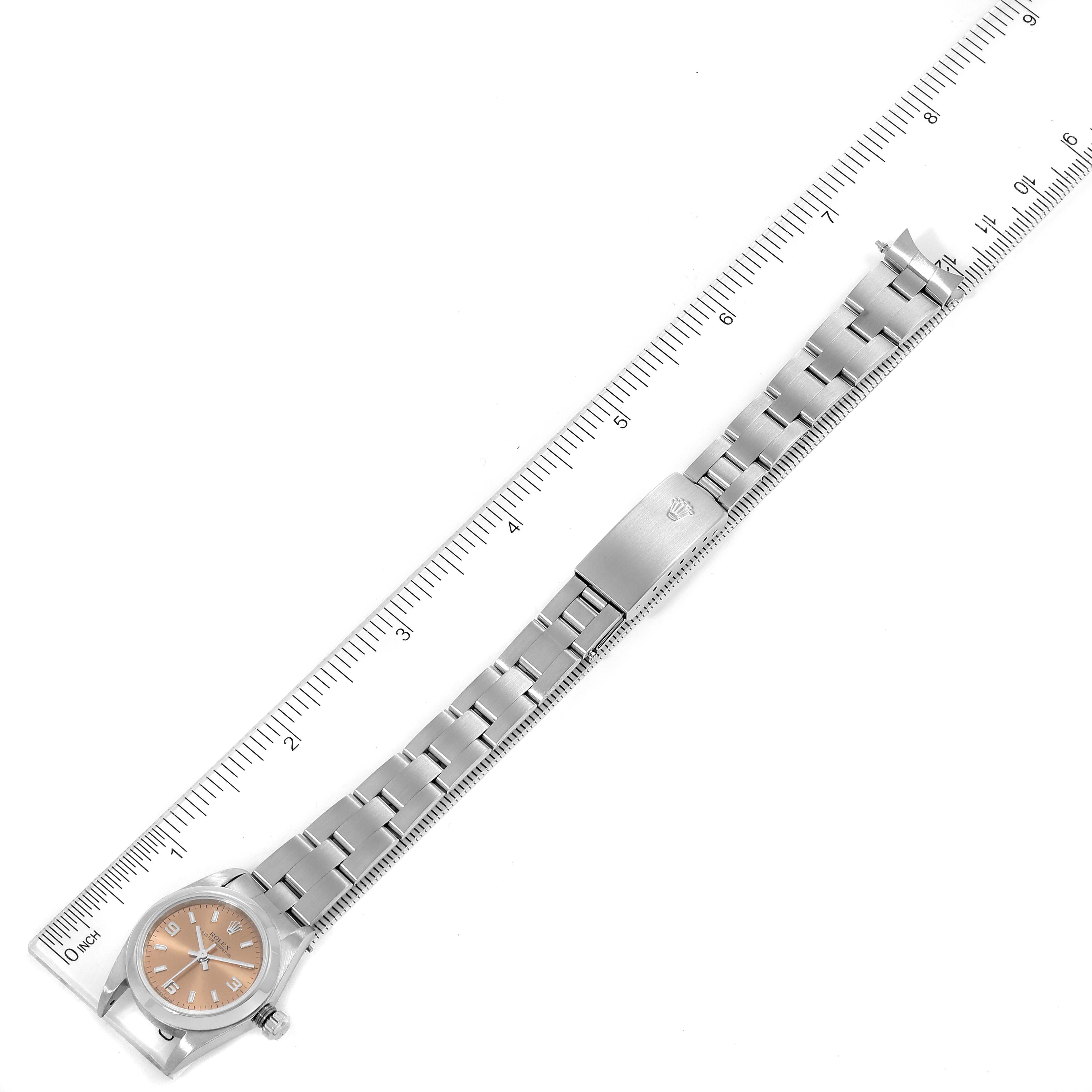 This image shows a Rolex Oyster Perpetual 76080 Women's Stainless Steel Pink Dial 76080 Women's Stainless Steel Pink Dial watch laid flat with a ruler alongside it for scale.