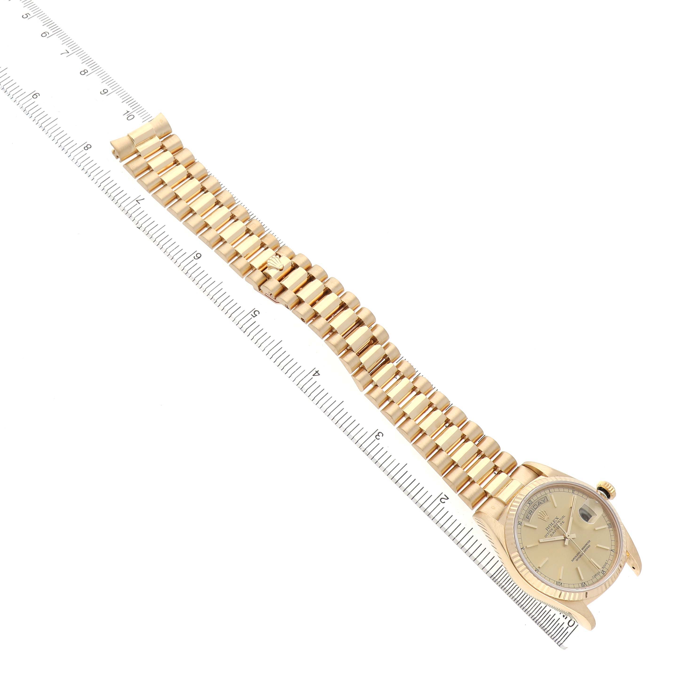 The Rolex President 18038 Men's Yellow Gold Champagne Dial watch is shown from an angled top view, displaying both the watch face and full bracelet along with a ruler for scale.