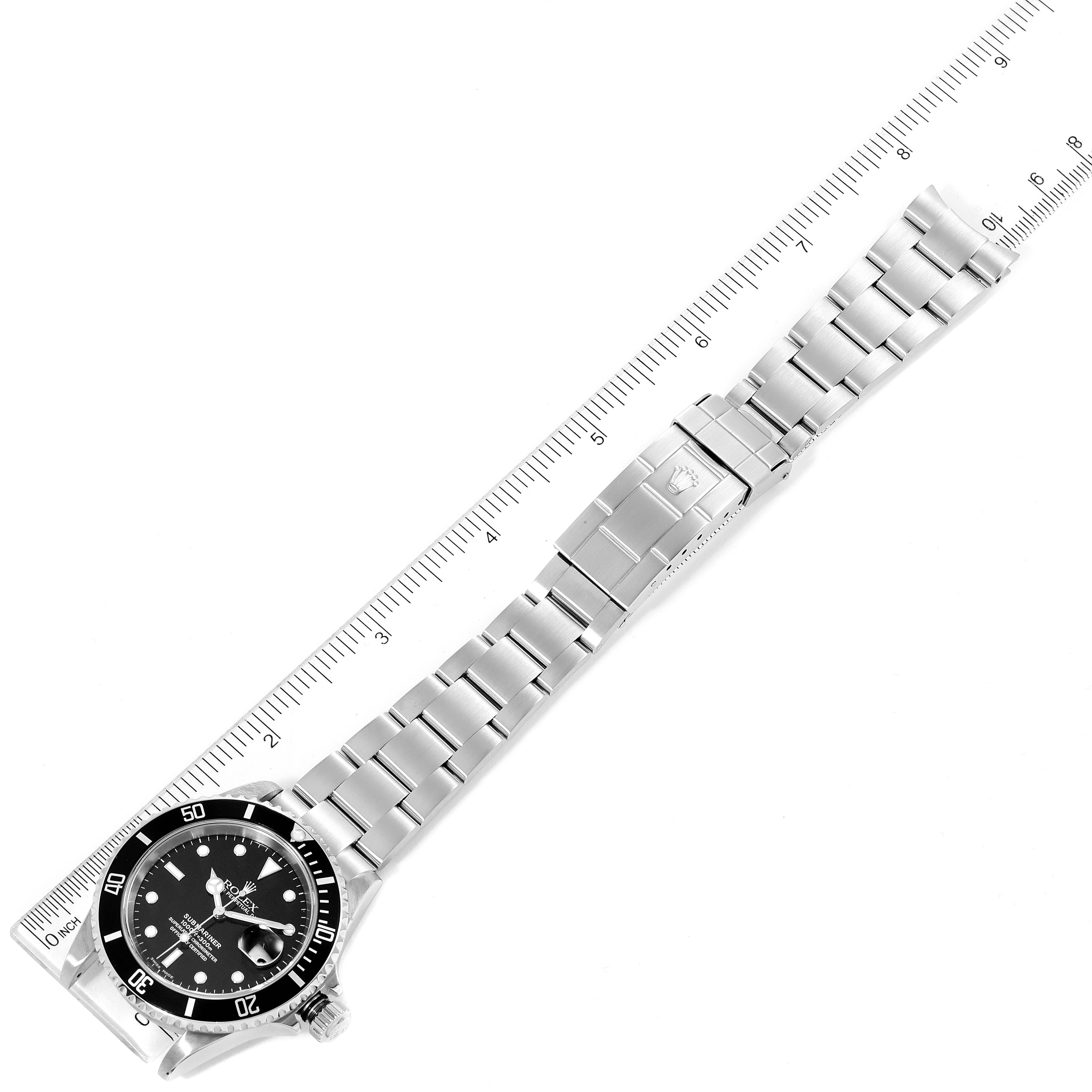 The image shows a full view of the Rolex Submariner 16610 Men
s Stainless Steel Black Dial 16610 Men
s Stainless Steel Black Dial watch, taken from above, with a ruler for scale.