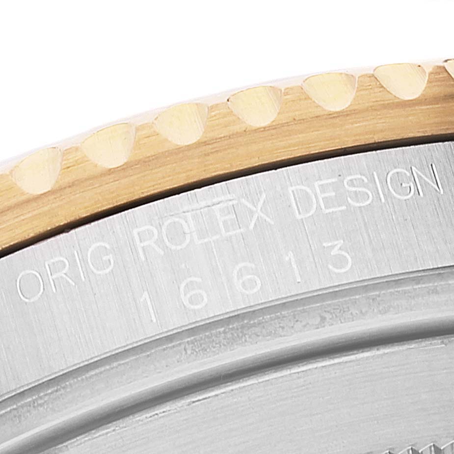 The image shows a close-up of the engraved case back of a Rolex Submariner 16613 Men
s Steel and Gold (two tone) Blue Dial 16613 Men
s Steel and Gold (two tone) Blue Dial, featuring its model number and a portion of its bezel.