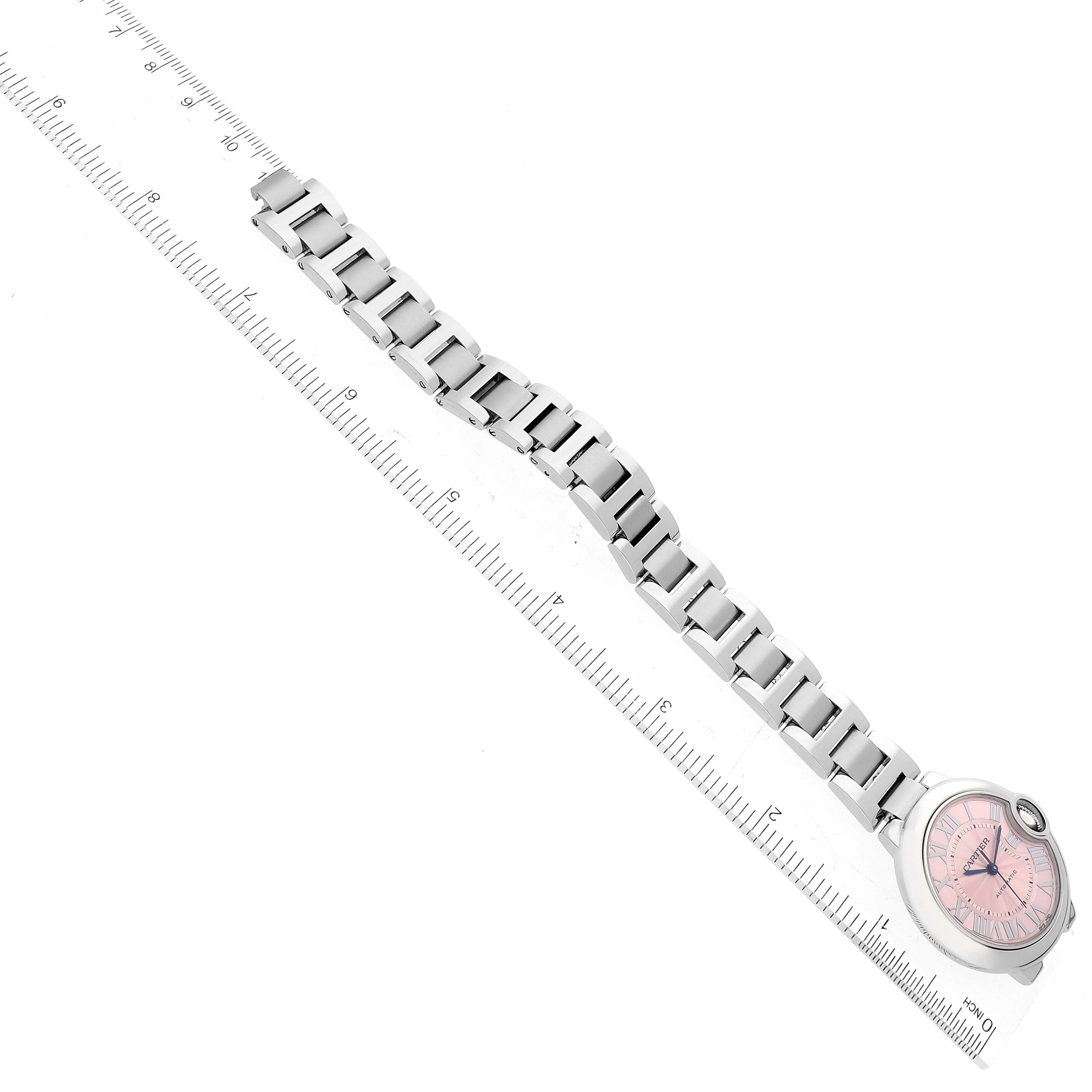 The image shows a Cartier Ballon Bleu W6920100 Women
s Stainless Steel Pink Dial W6920100 Women
s Stainless Steel Pink Dial watch viewed from above, highlighting its metal bracelet and pink dial, placed next to a ruler.